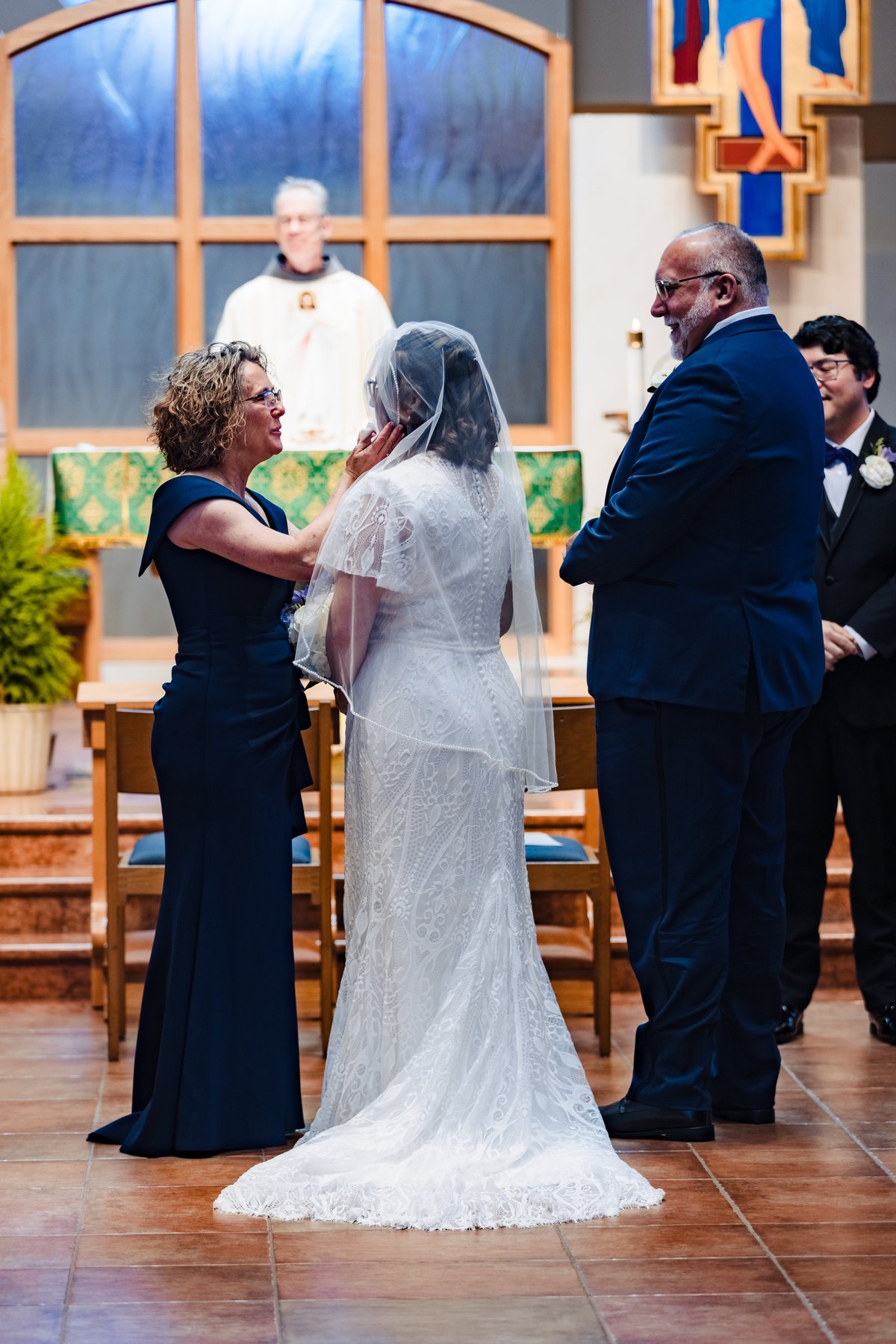 The bride's mother lifts her veil at the altar before the exchange of consent