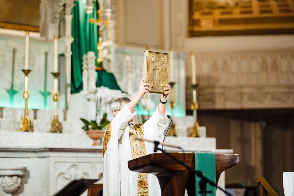 The priest elevates the Book of the Gospels after proclaiming the Gospel at the Catholic wedding Mass