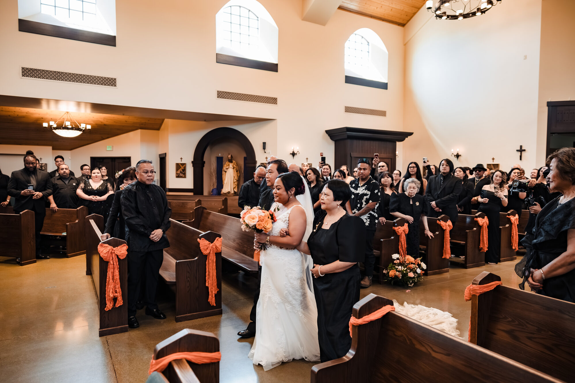 Groom watching his bride process down the aisle during the Catholic wedding Mass
