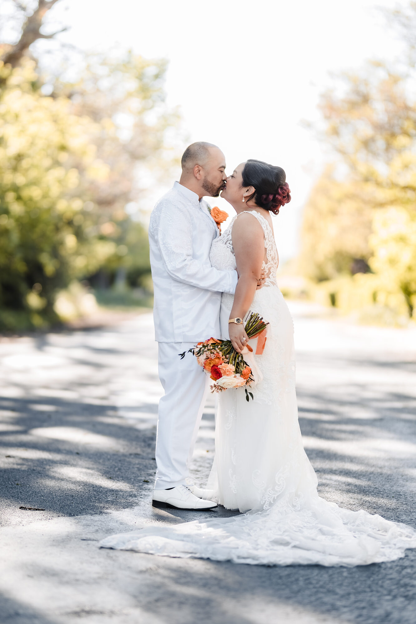 Bride and groom kissing on a tree-lined road at Park Winters