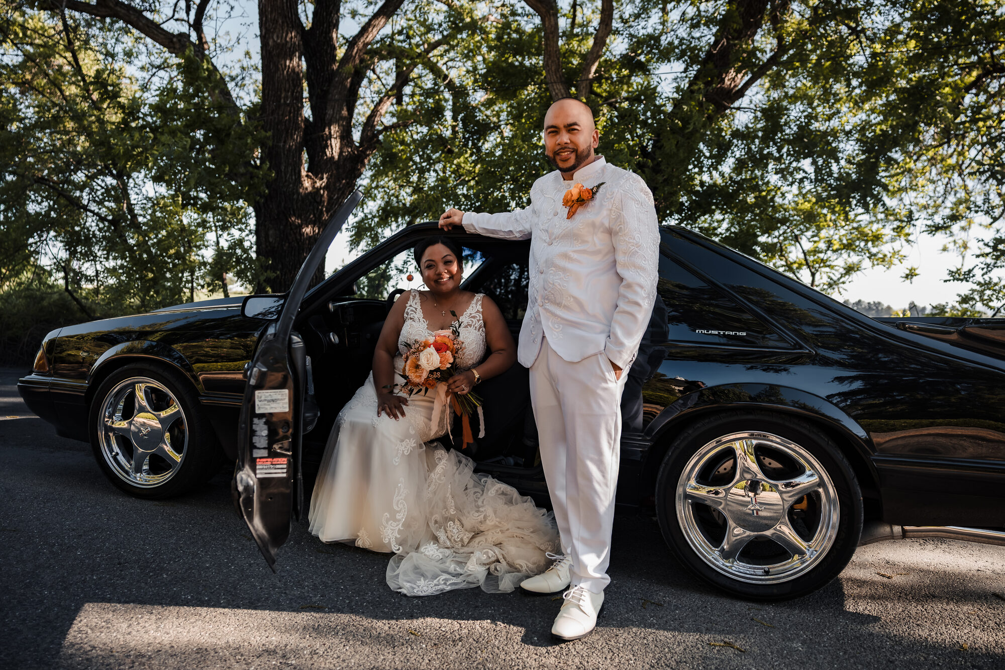 Bride and groom posing with a classic black Mustang at Park Winters