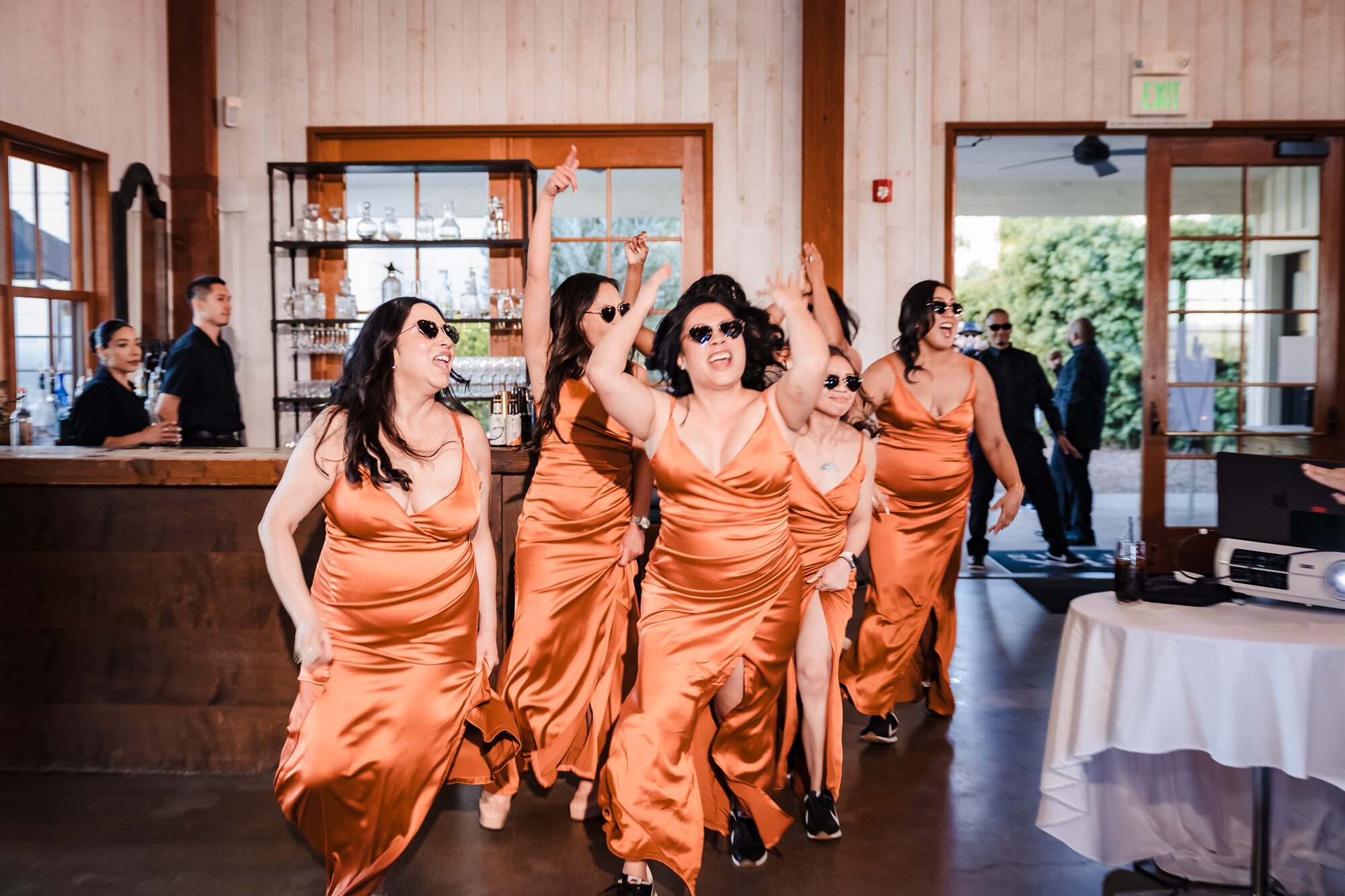 Bridesmaids in copper dresses dancing into the Park Winters reception hall