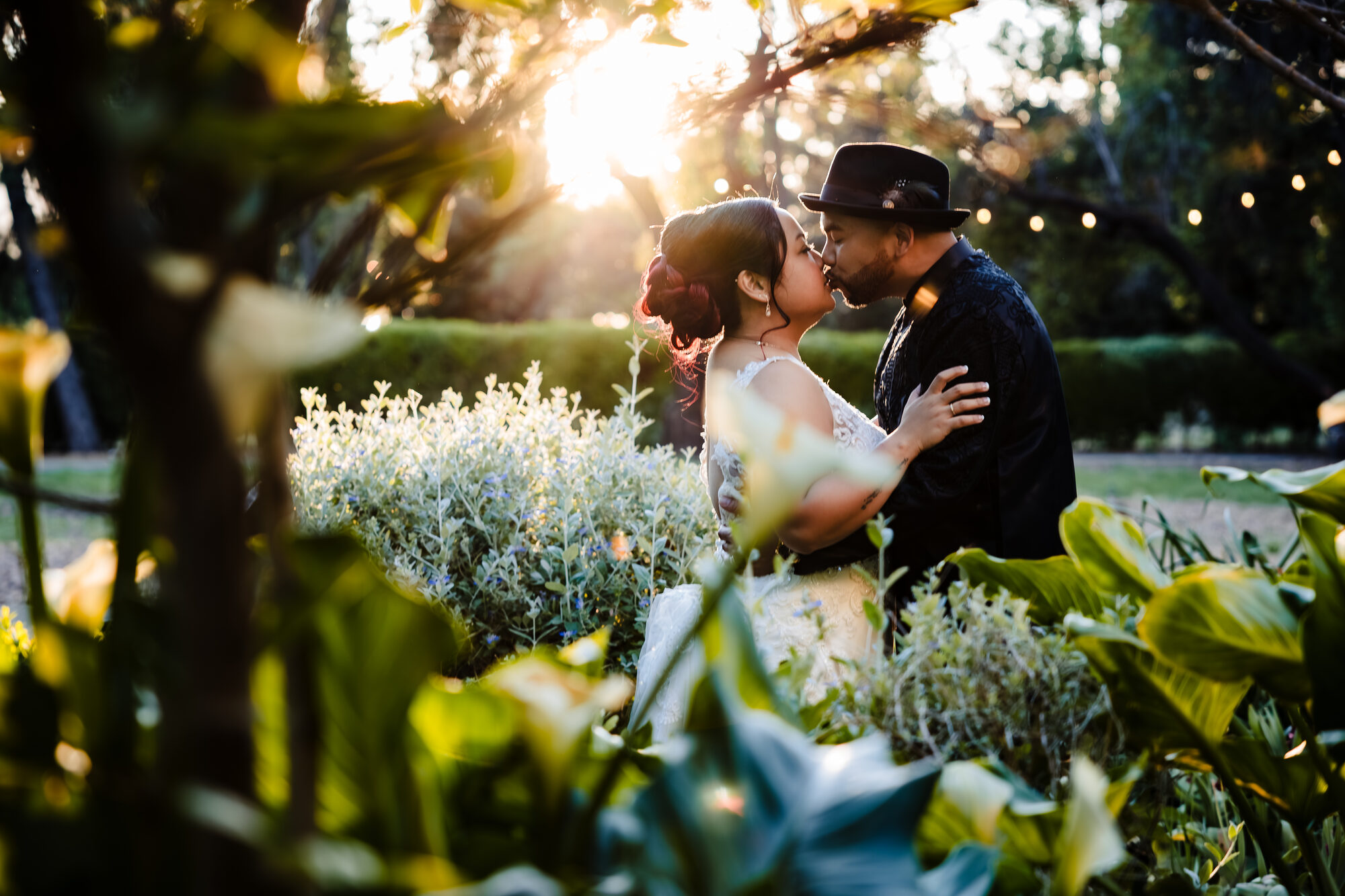 Bride and groom kissing under string lights at sunset, Park Winters