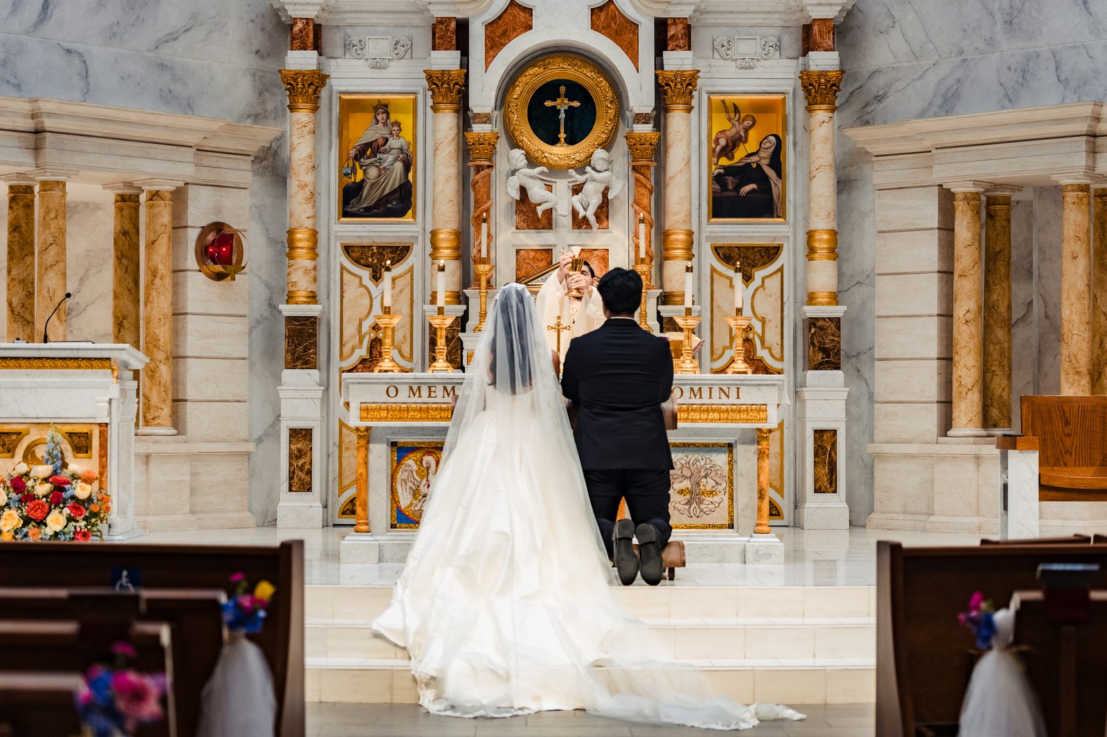 A priest who is the couple's own catechist elevates the consecrated Host at a Neocatechumenal Way wedding