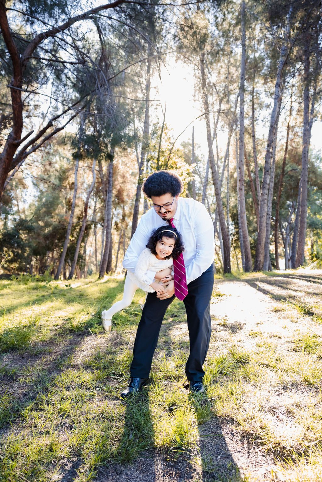 A father and young daughter sharing a playful moment outdoors