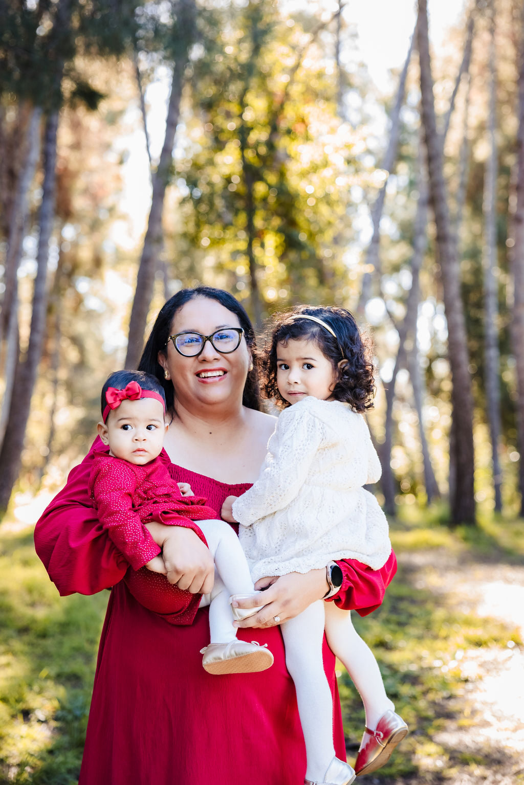 A mother holding her two young daughters outdoors