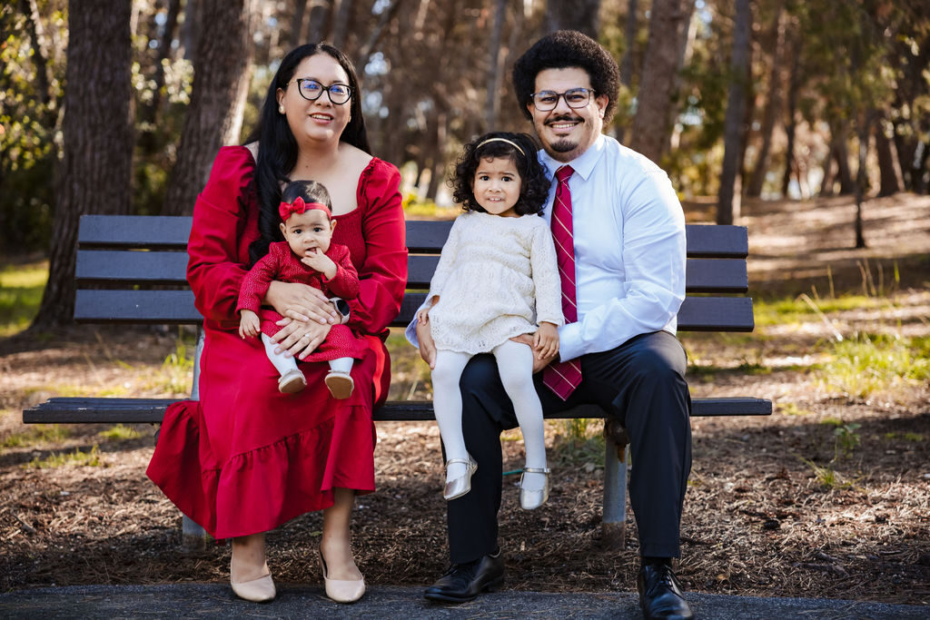 A family of four seated together on a park bench