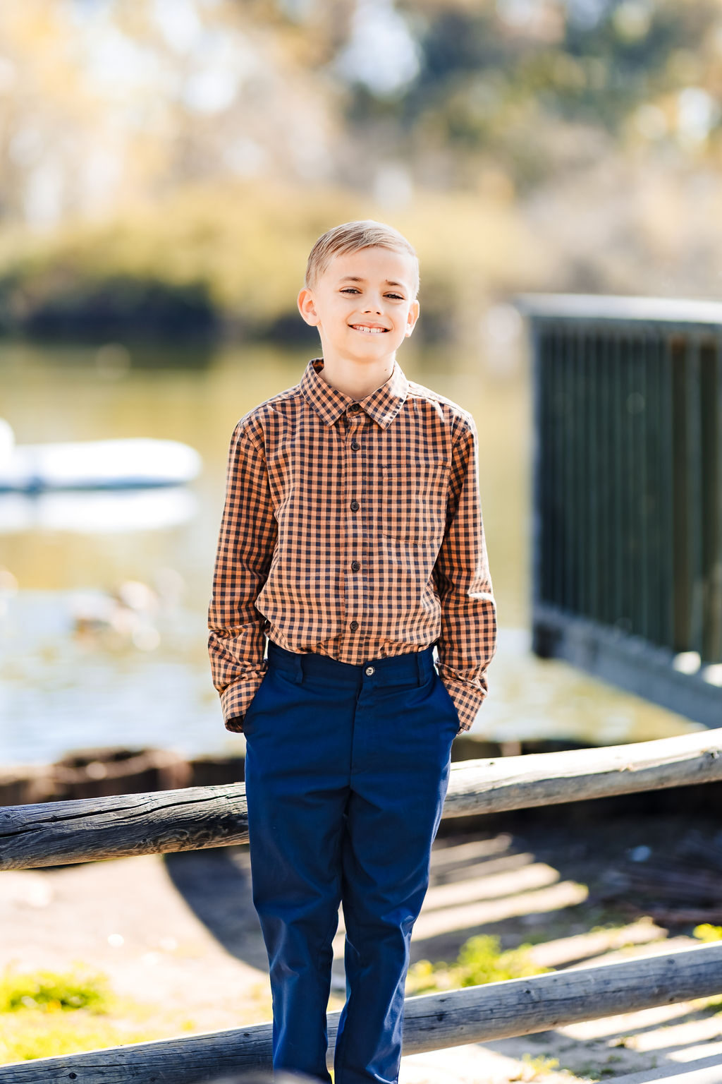 A young boy in a collared shirt smiling outdoors