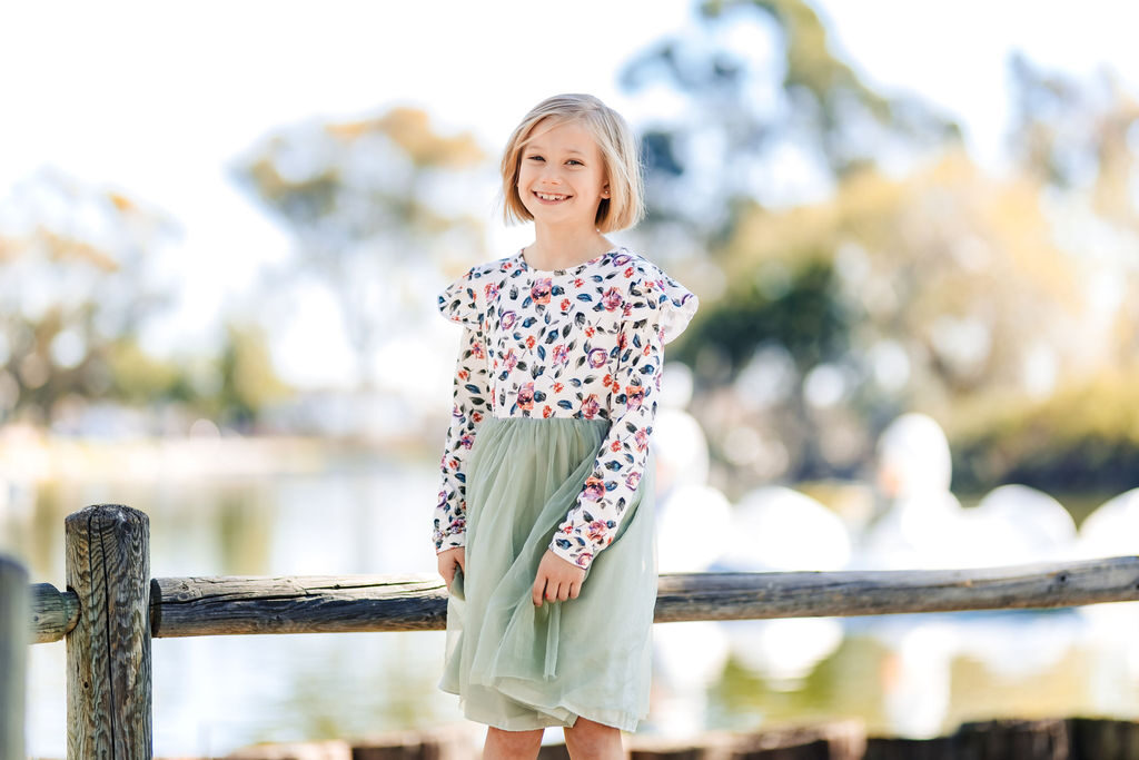 A young girl in a floral dress by the water