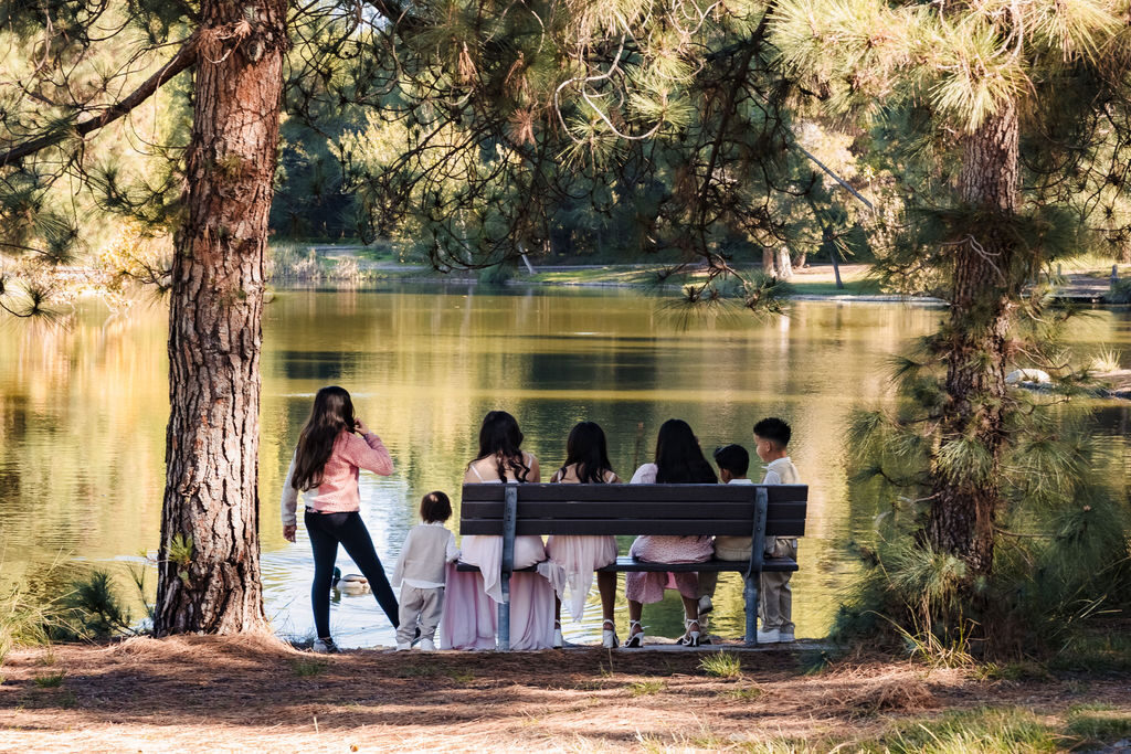 Children sitting together on a bench by a lake at golden hour