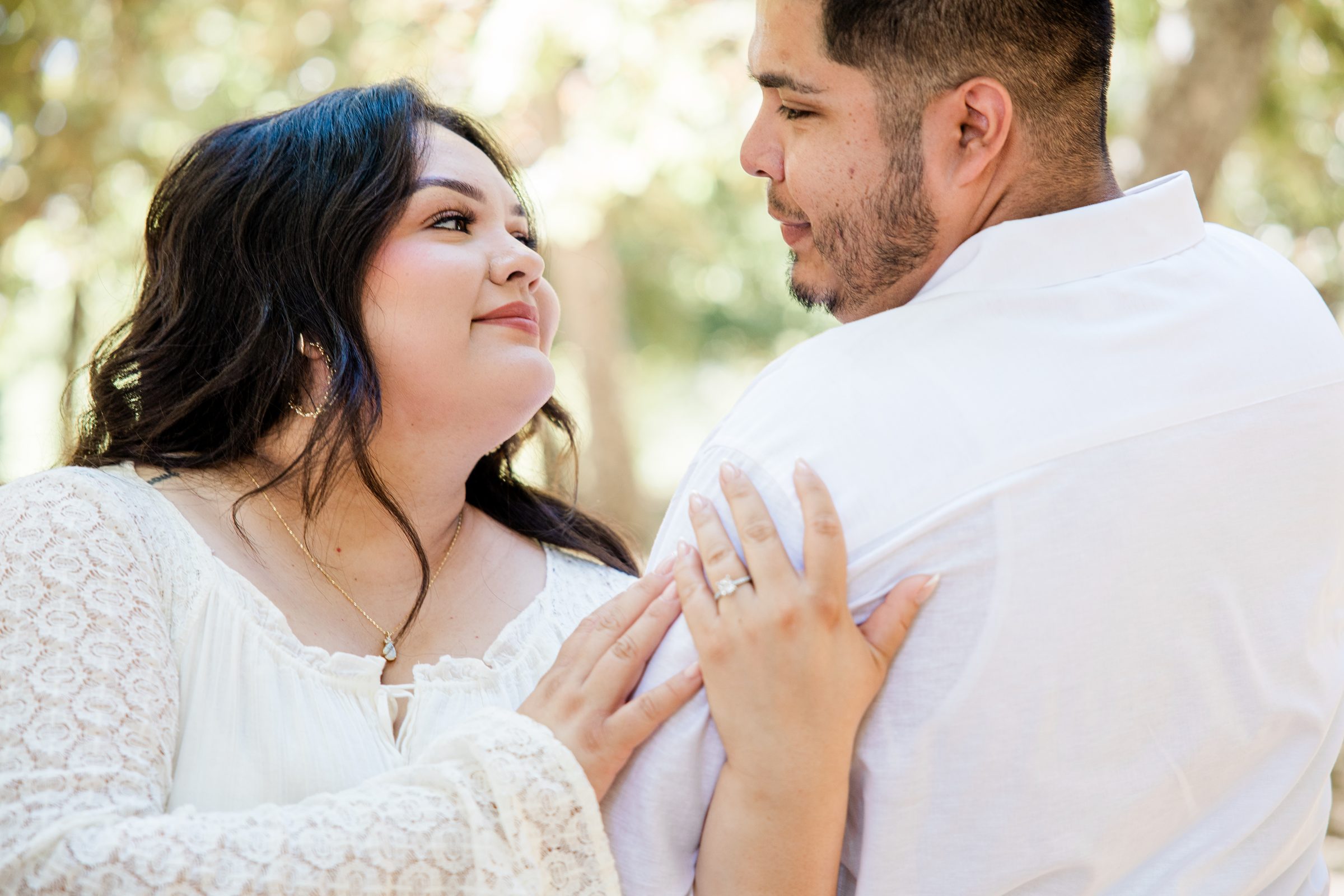 Cristina's hand and engagement ring resting on Eric's shoulder during their engagement portraits