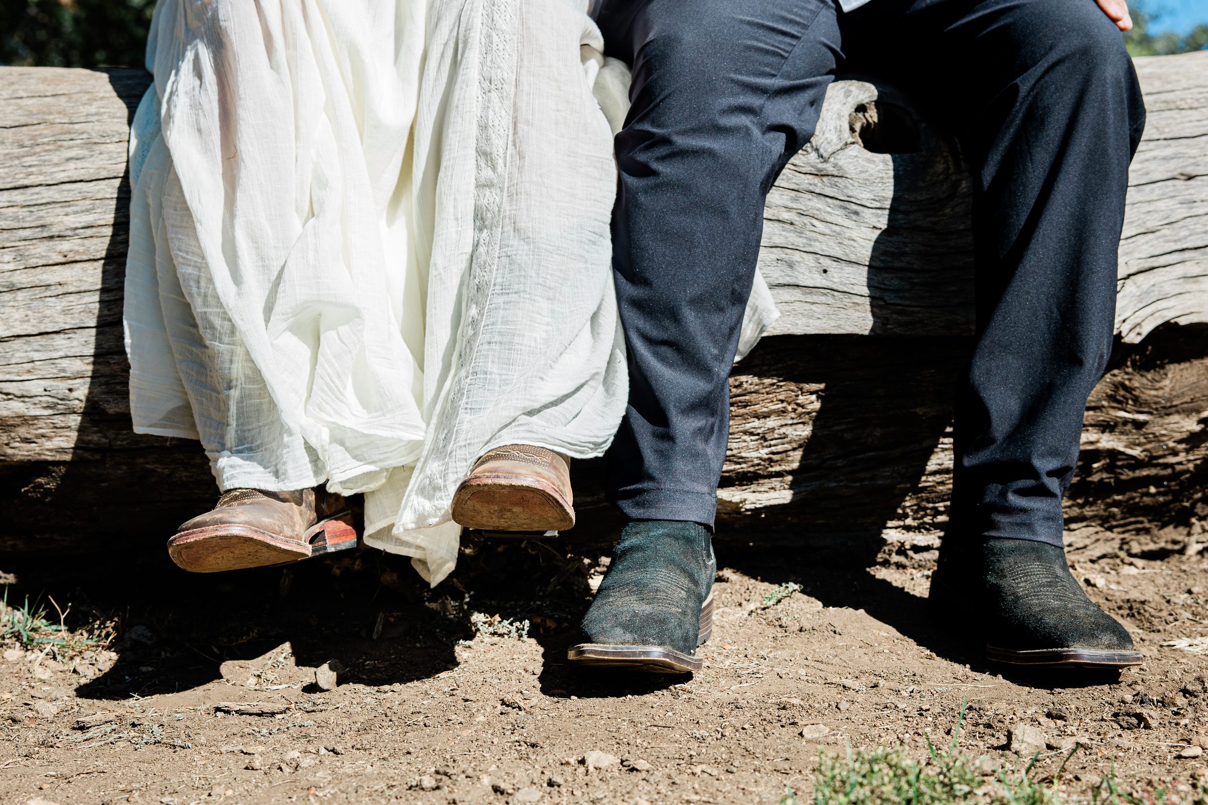 Detail of Cristina's ivory dress and the couple's shoes on a rustic log bench at Oak Glen Preserve