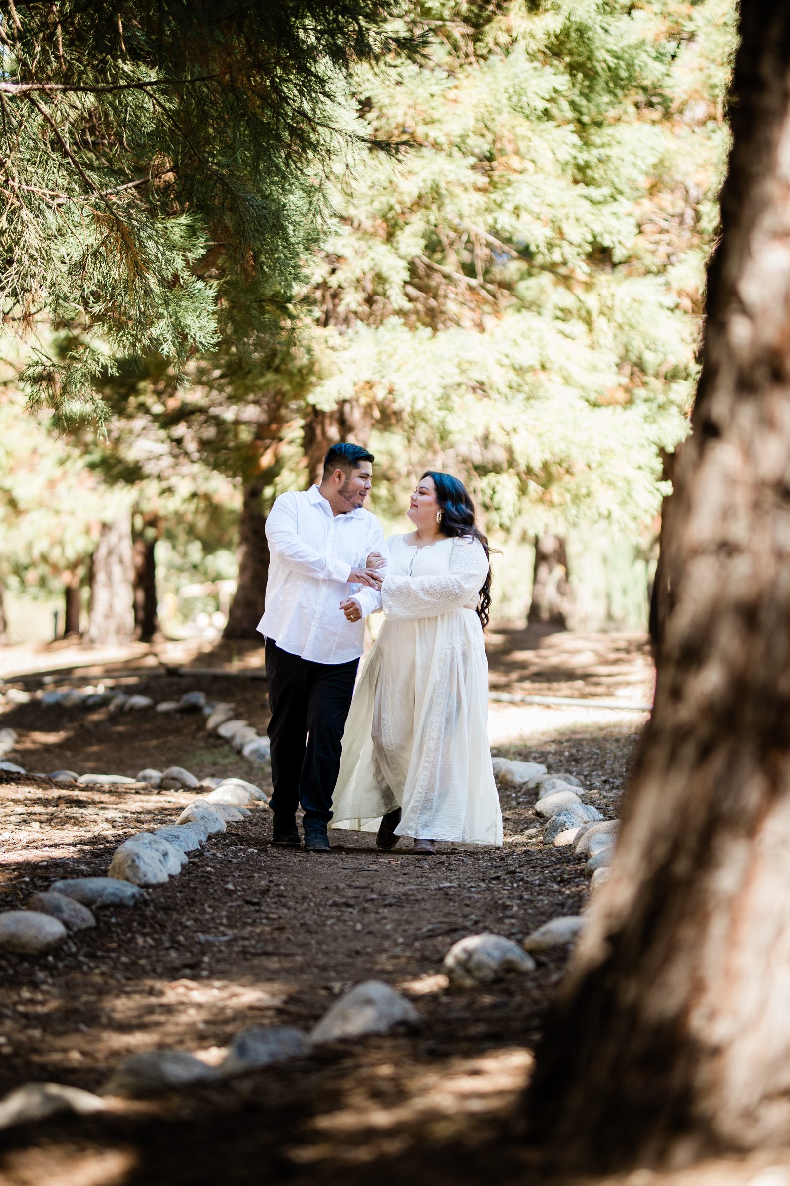 Eric and Cristina walking a stone-lined path through the pines at Oak Glen Preserve
