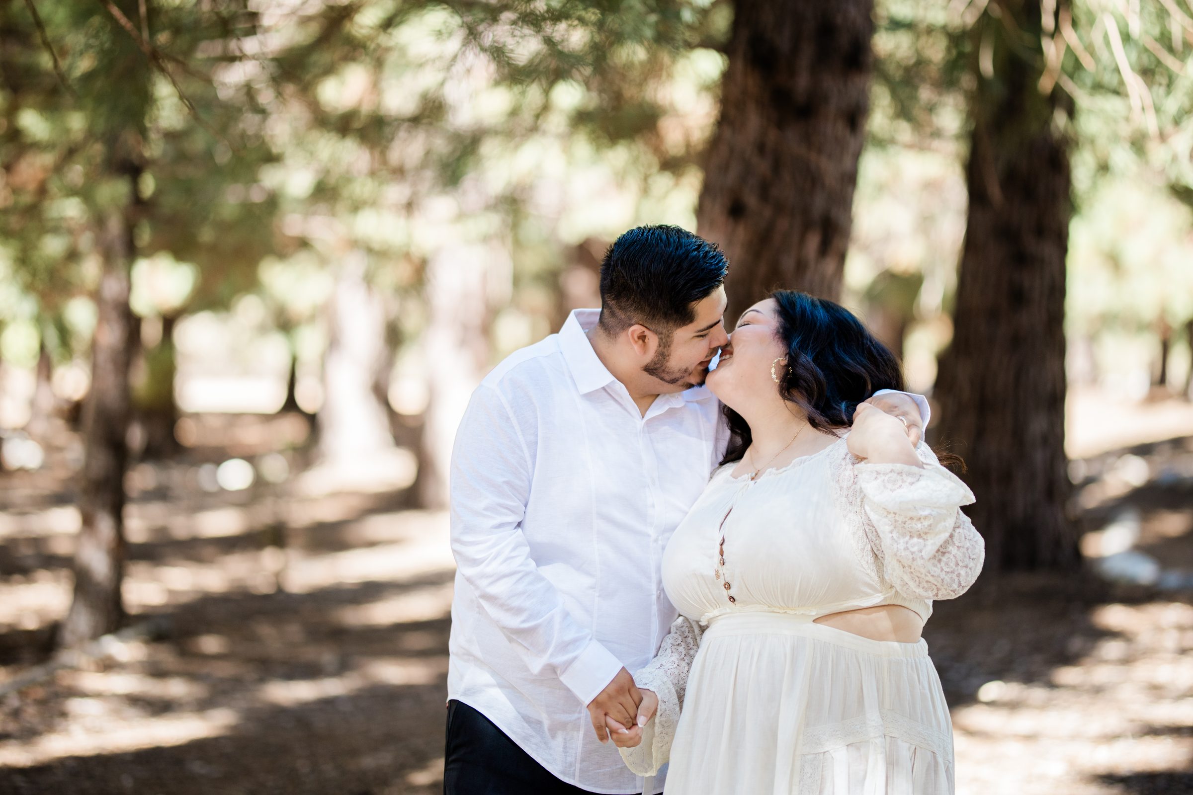 Eric and Cristina sharing a kiss in the forest at Oak Glen Preserve