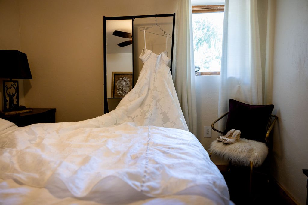 The wedding gown laid across the bed in a cabin at Aspen Falls