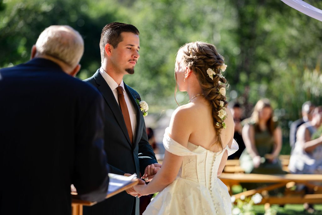 The groom smiling at his bride during the ceremony