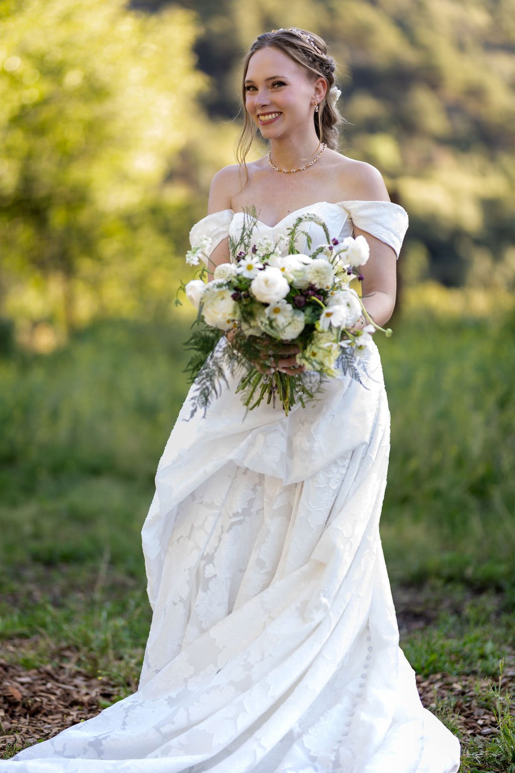 The bride smiling with her bouquet in the meadow