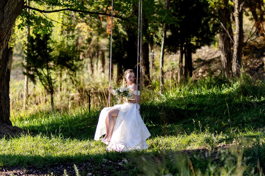 The bride on the swing in the green meadow