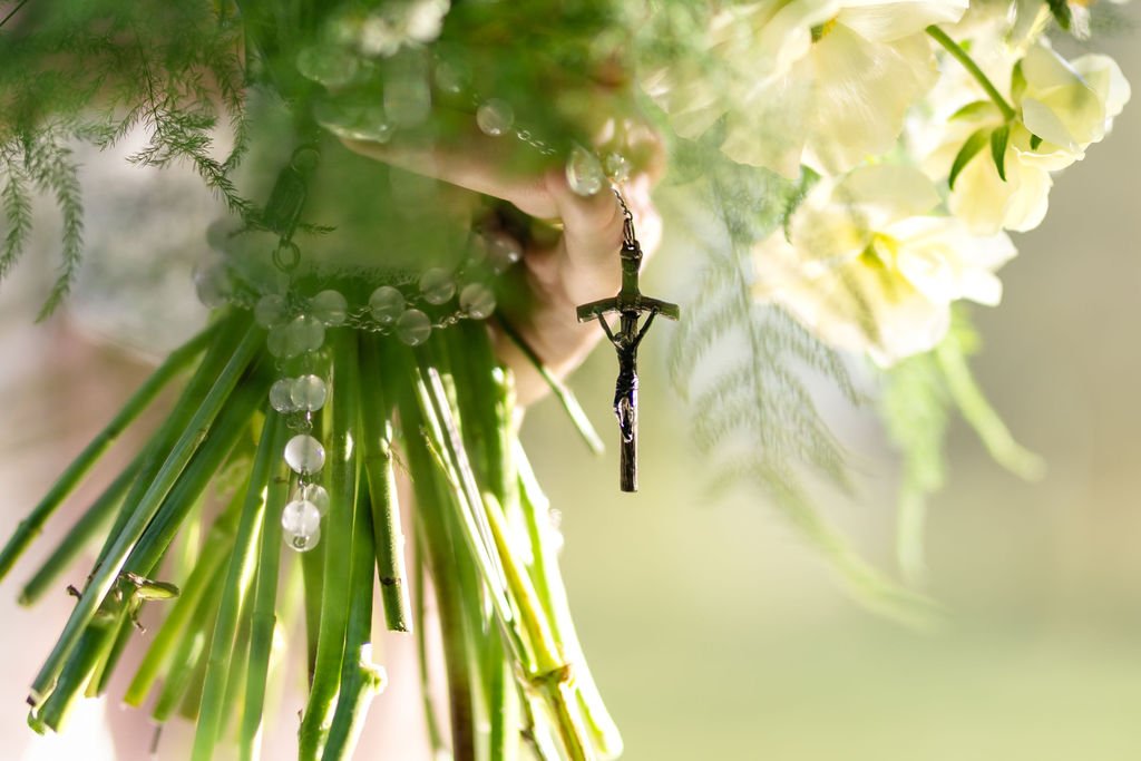 A small crucifix tucked into the bride's white bouquet