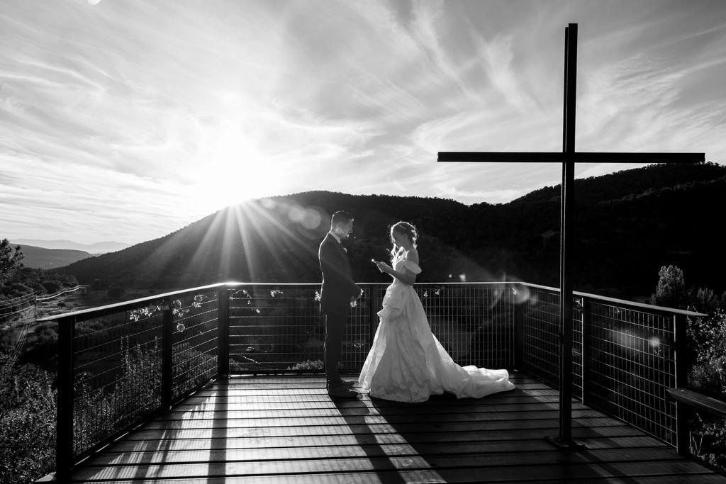 Black and white silhouette of the couple and the cross against the setting sun