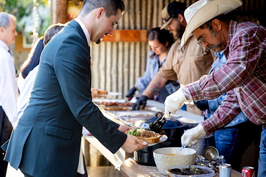 The groom at the buffet line beneath the pavilion