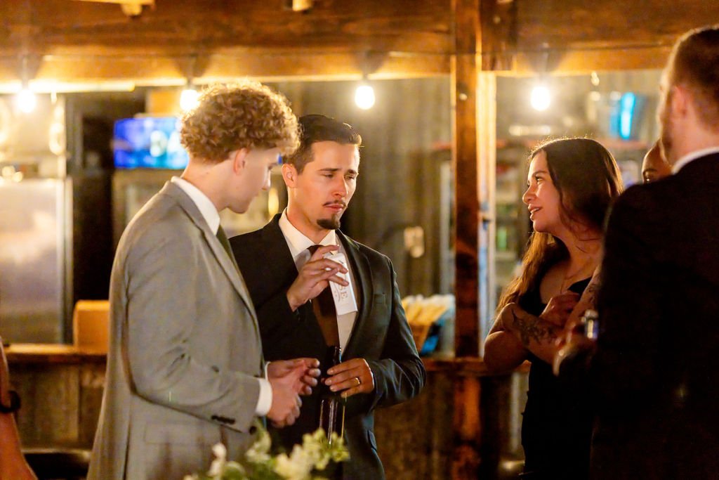 The groom laughing with guests at the reception