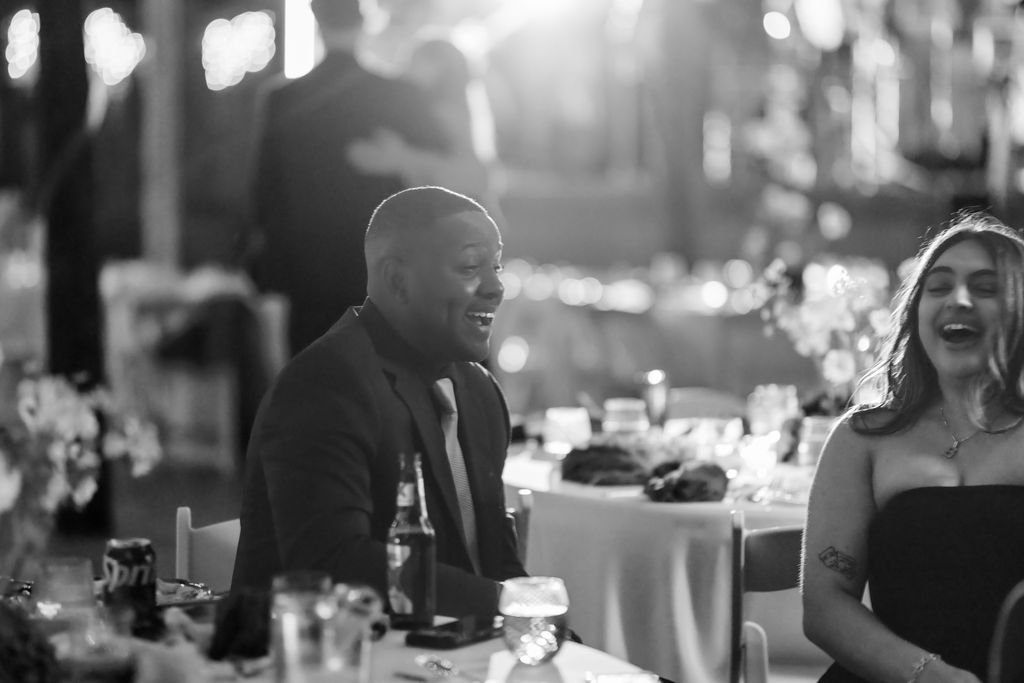 Black and white of guests laughing at dinner