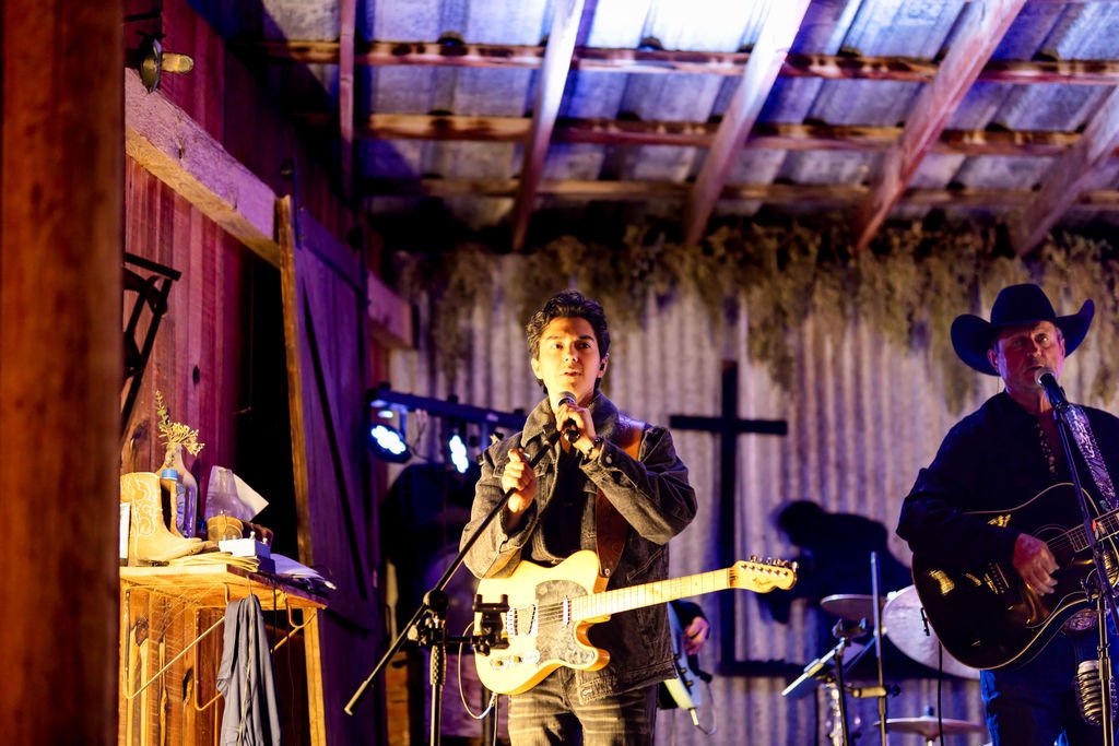 The band singer under the stage lights with a cross behind them