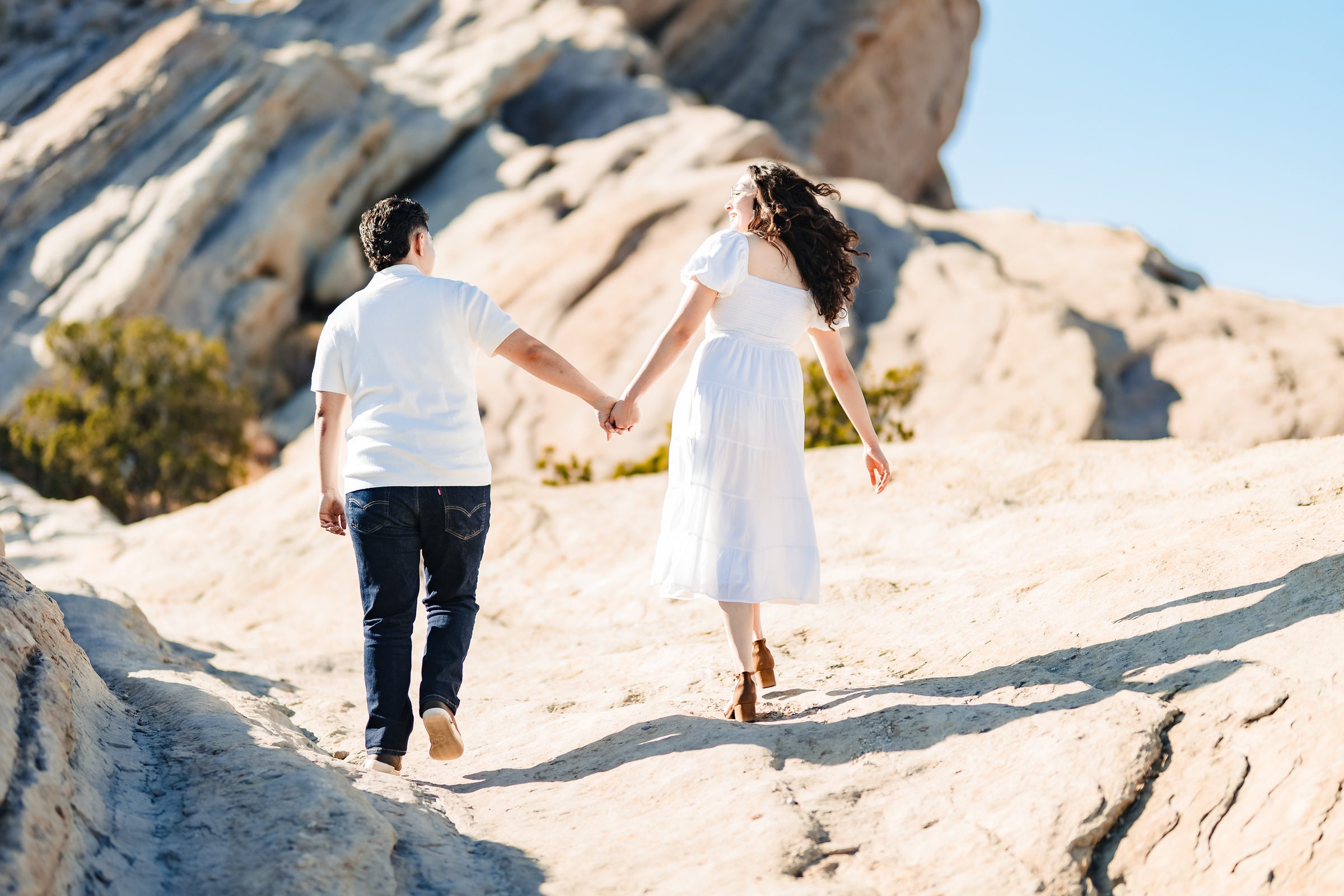 The couple walking hand in hand up the sandstone ridge