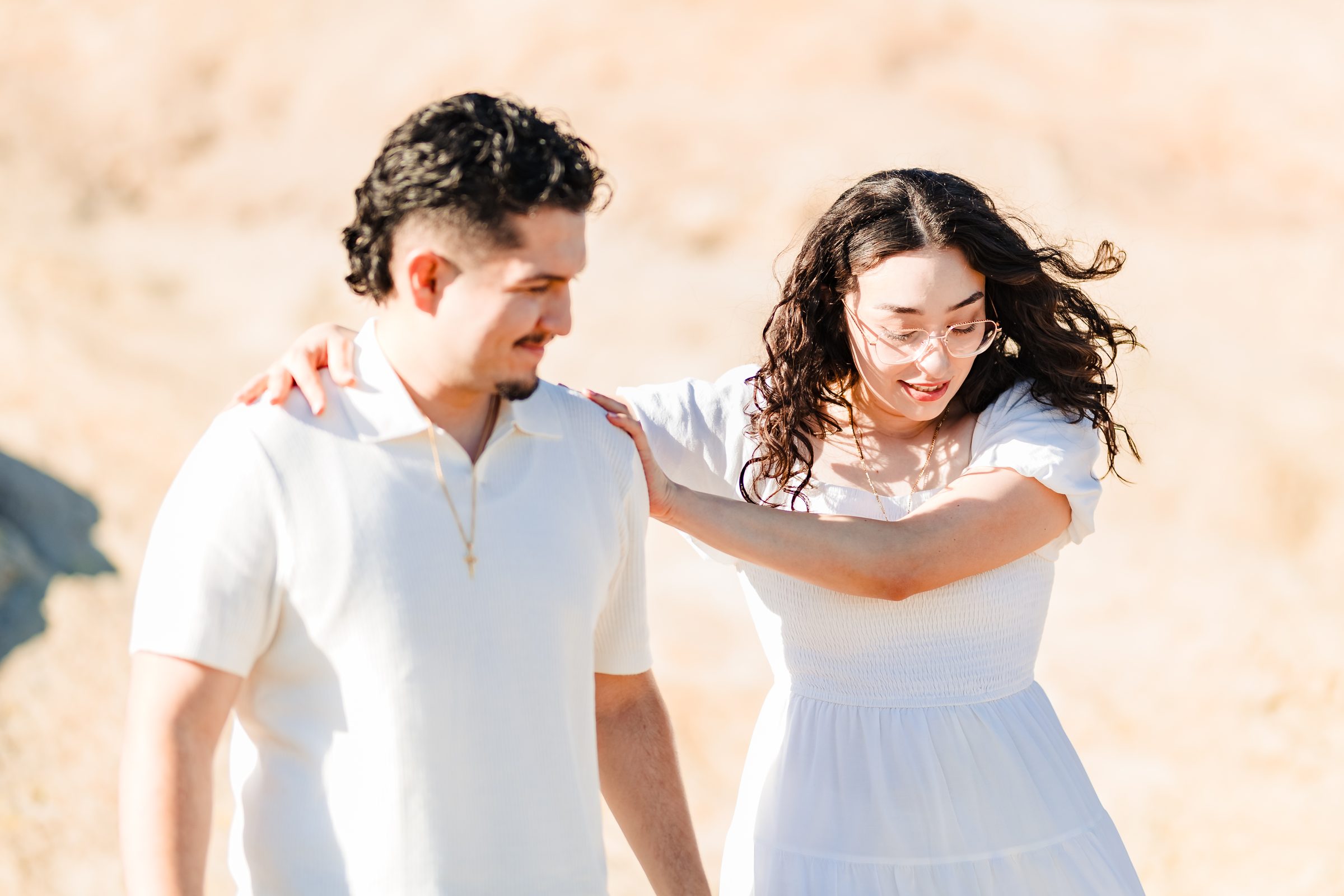 Daniela laughing behind Enrique as her curls catch the wind