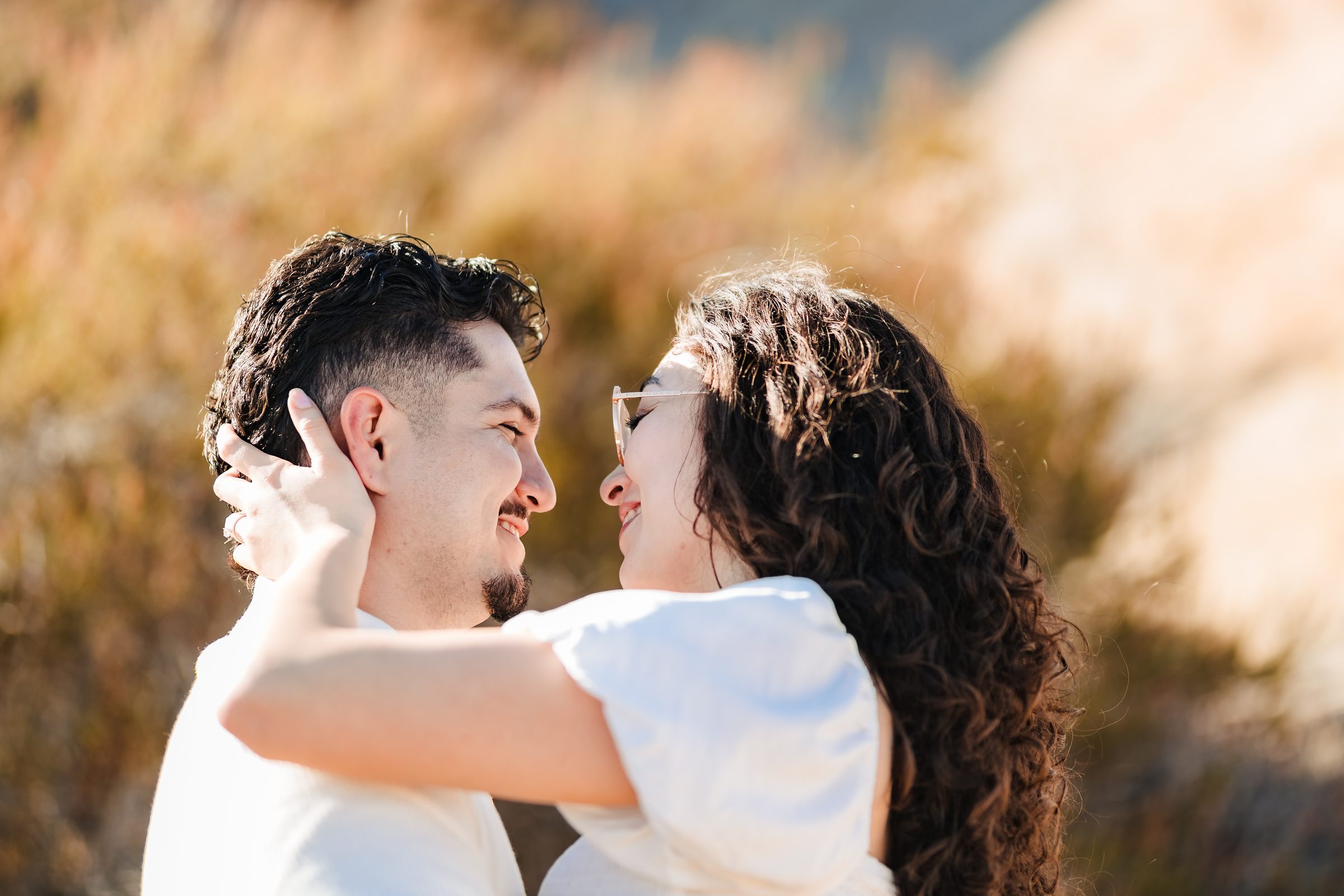 Close portrait of Daniela holding Enrique's face in golden light