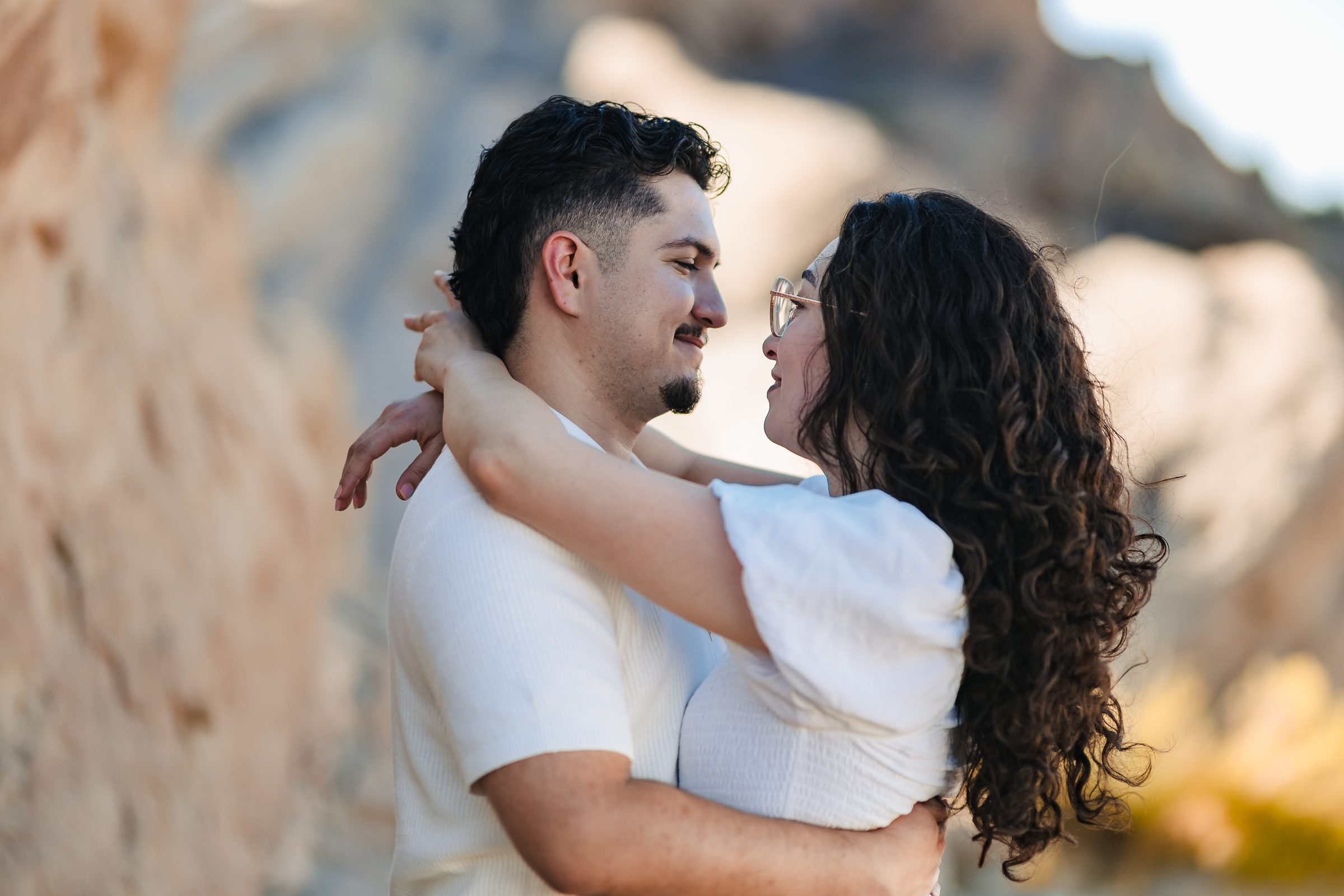 Daniela's arms around Enrique's neck in warm afternoon light