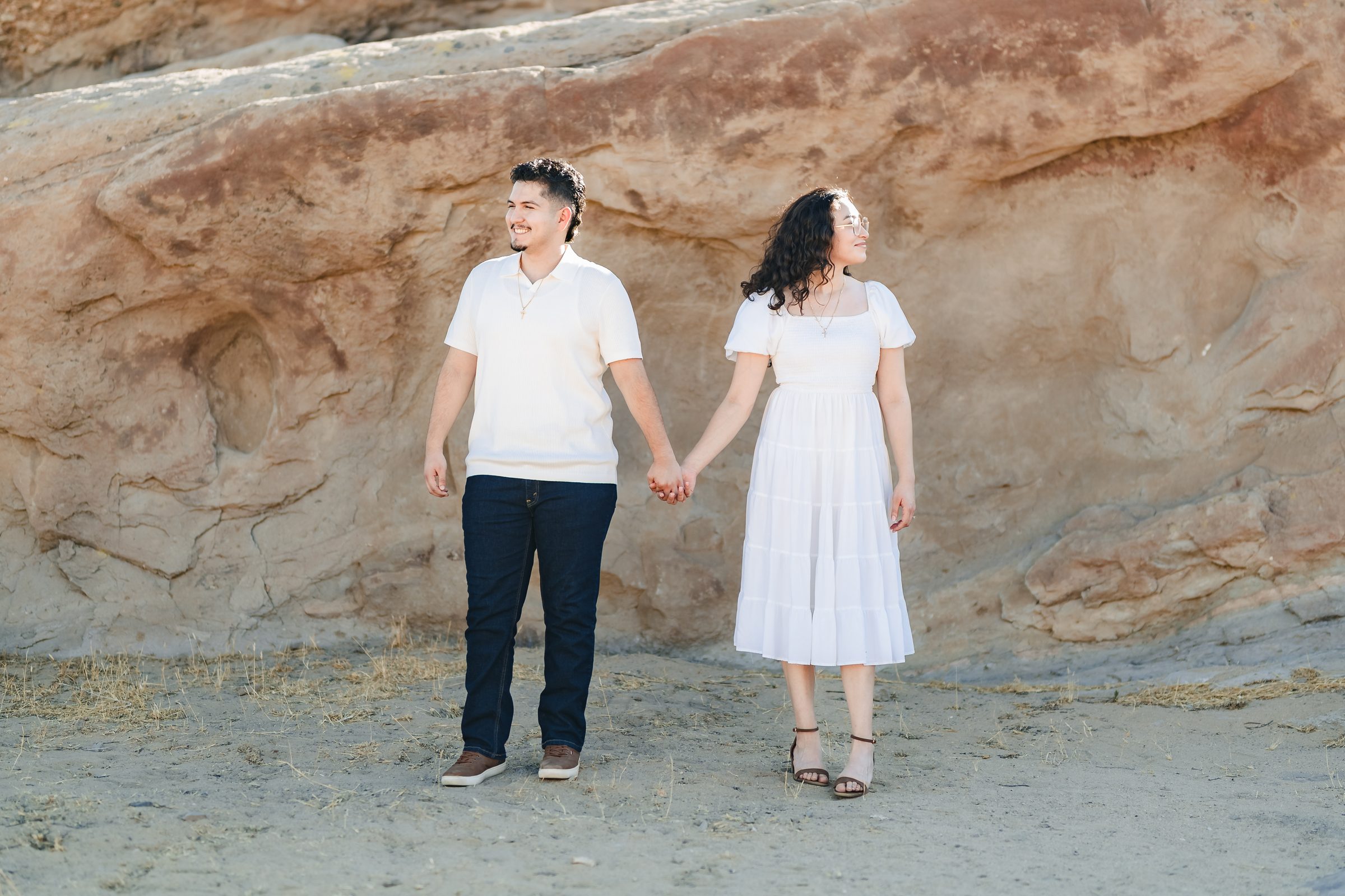 Enrique and Daniela holding hands in front of a red sandstone wall