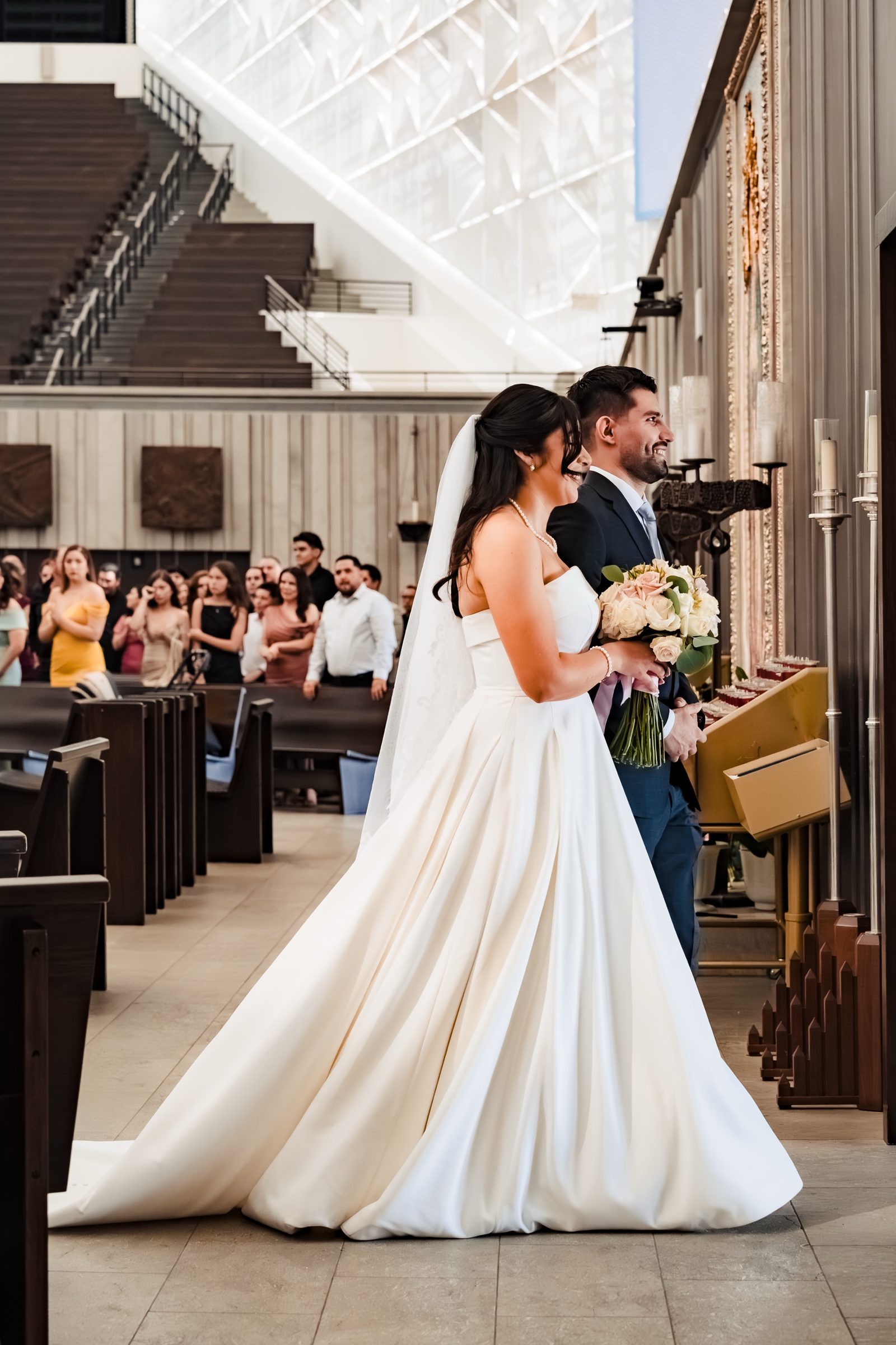 A bride and groom smiling at the altar of Christ Cathedral, Garden Grove