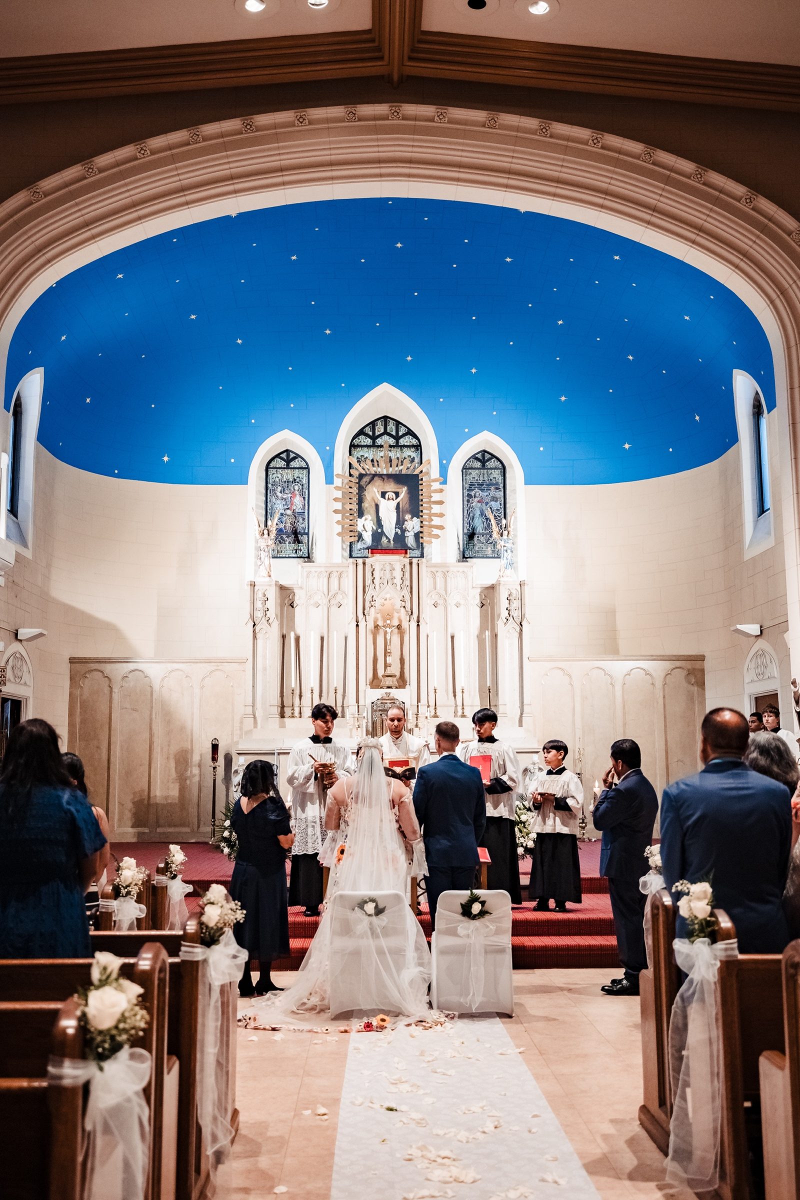 A couple kneeling before the Gothic high altar and starry blue apse of Our Lady of Refuge in the Bronx