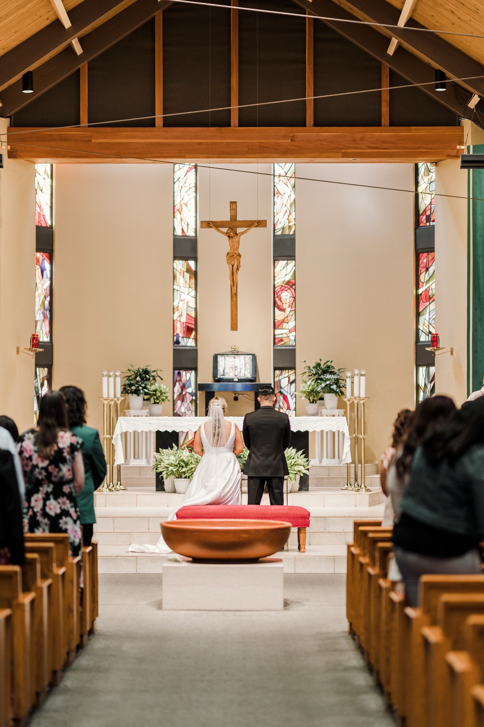 A couple kneeling before the altar and hanging crucifix at St. Irenaeus, Cypress