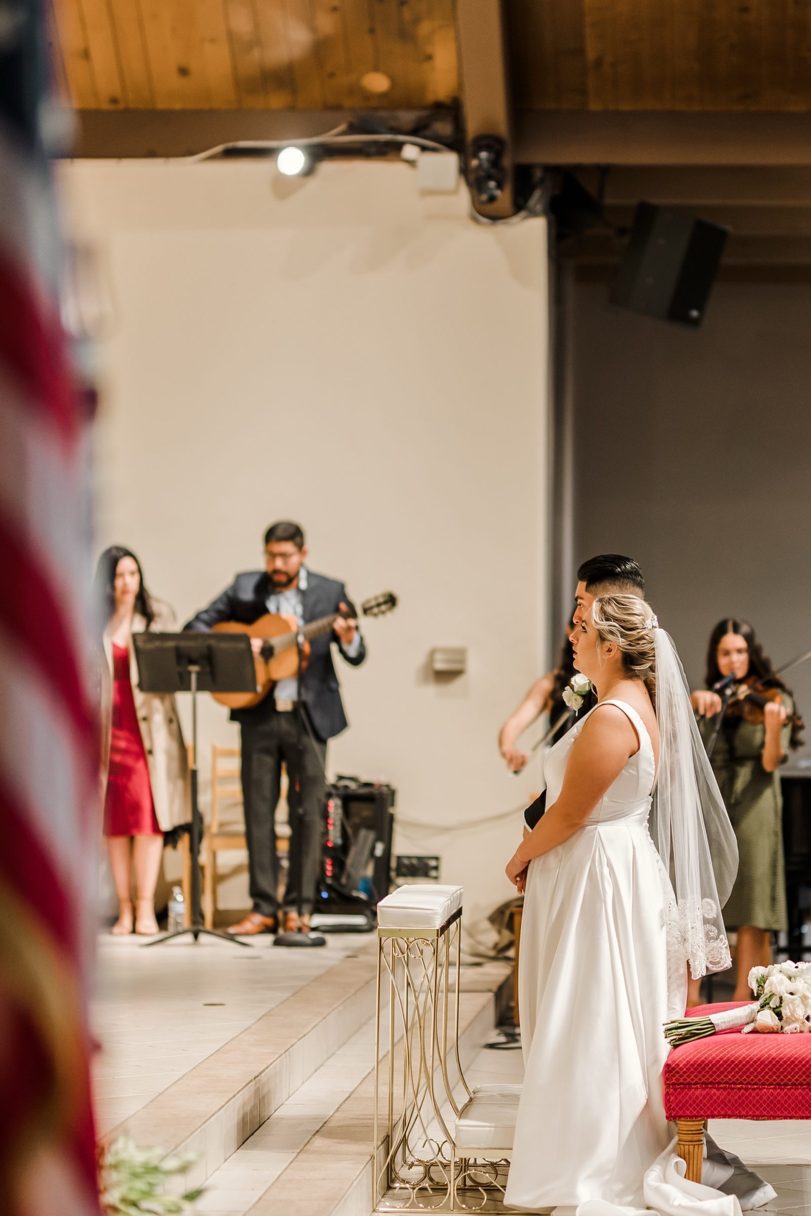 A bride and groom at the altar as musicians play at St. Irenaeus