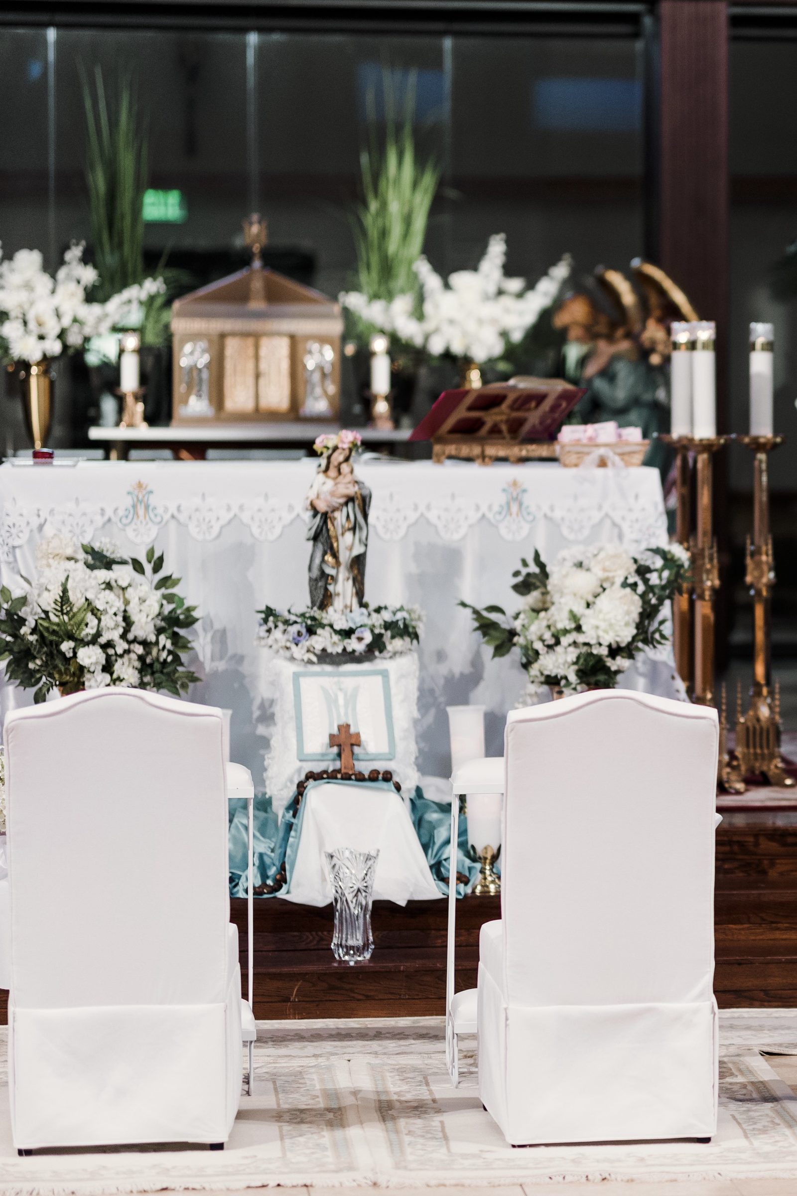 A statue of Our Lady crowned with flowers and a rosary before the altar at St. Mark the Evangelist