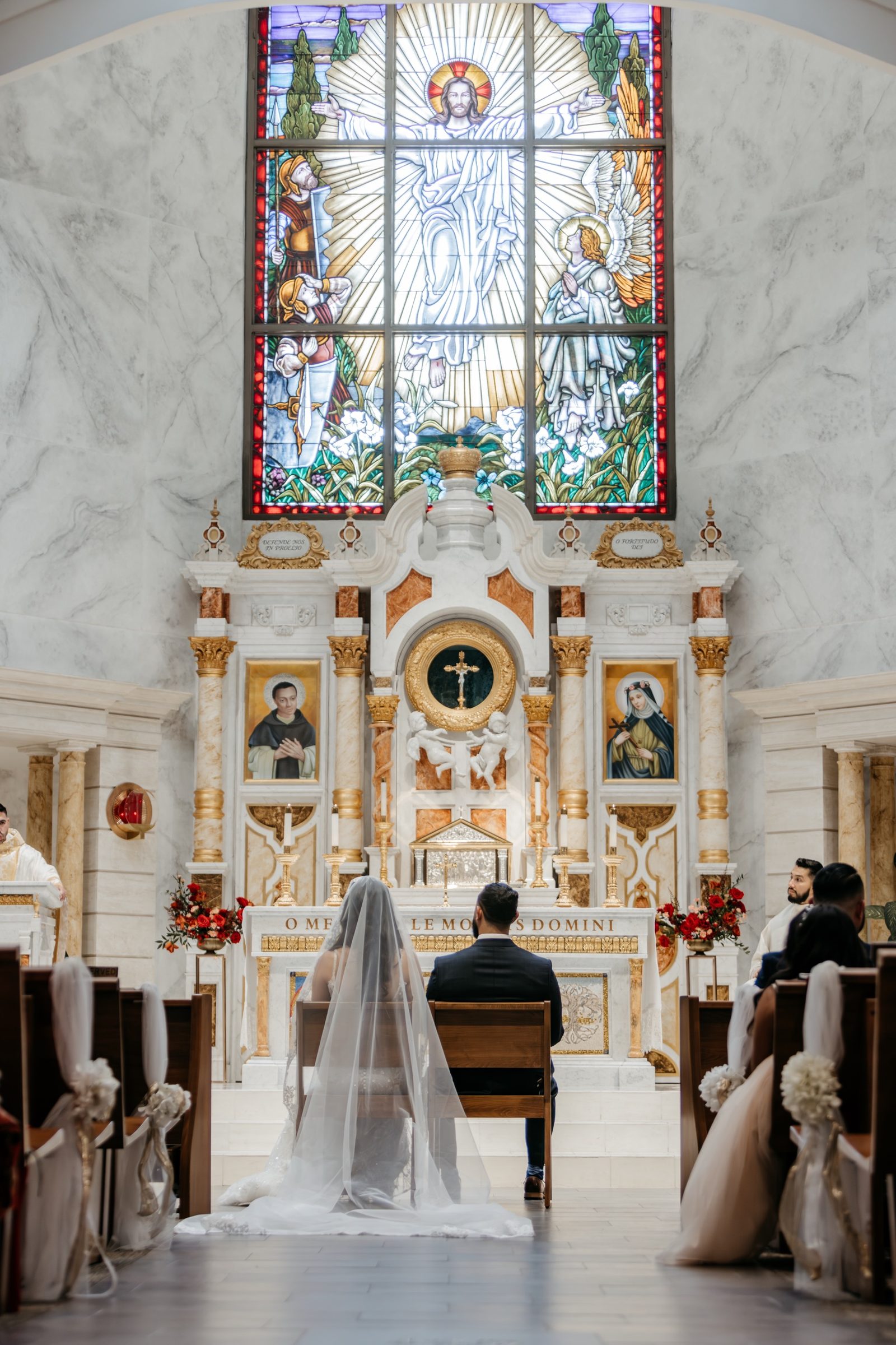 A bride and groom seated before the marble and gold high altar of St. Martin de Porres, Yorba Linda