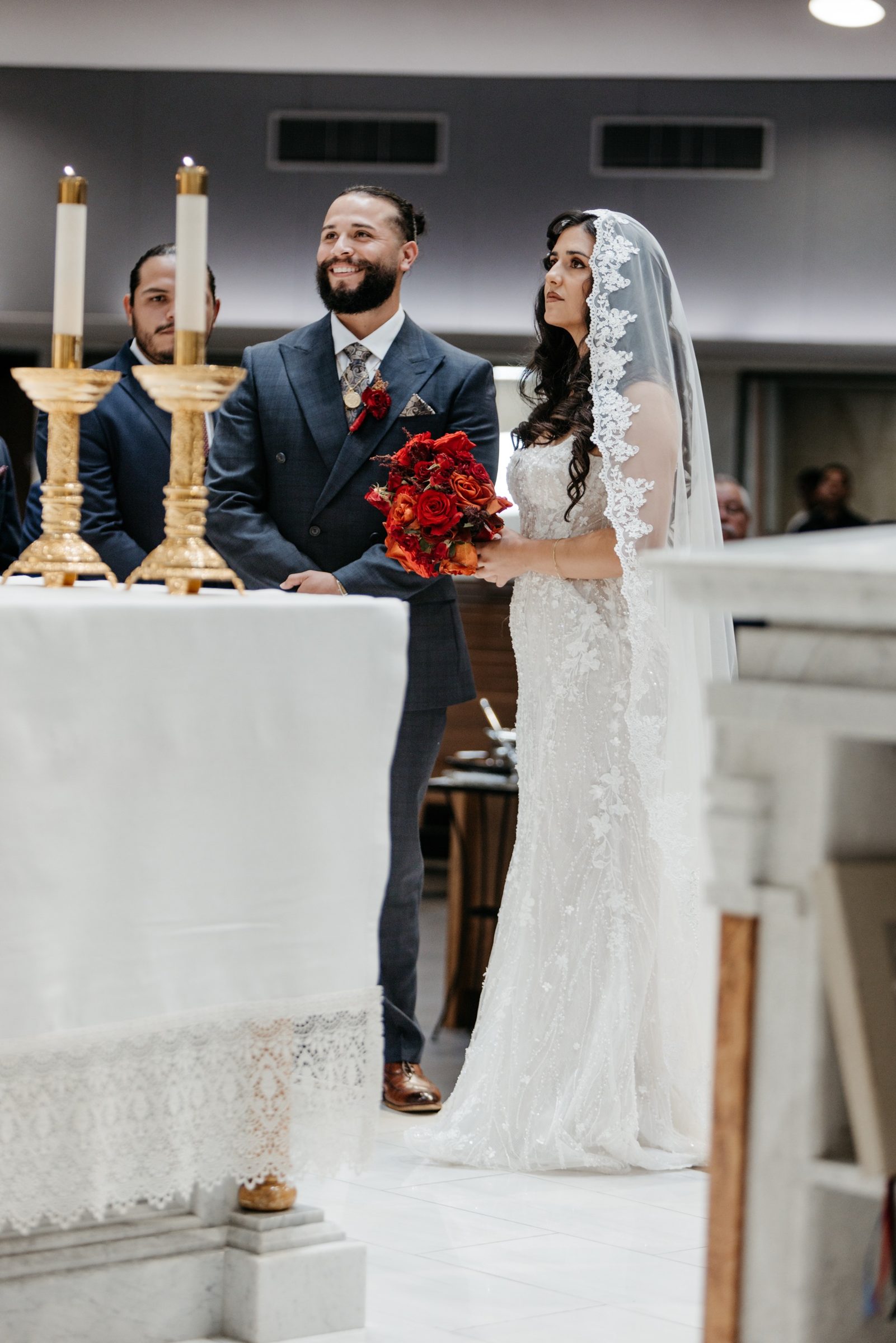 A couple at the altar of St. Martin de Porres holding a red rose bouquet