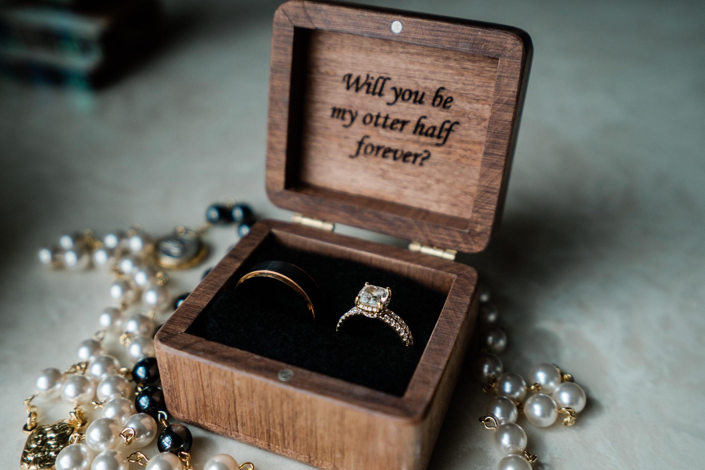 Wooden ring box engraved Will you be my otter half forever, beside a pearl rosary