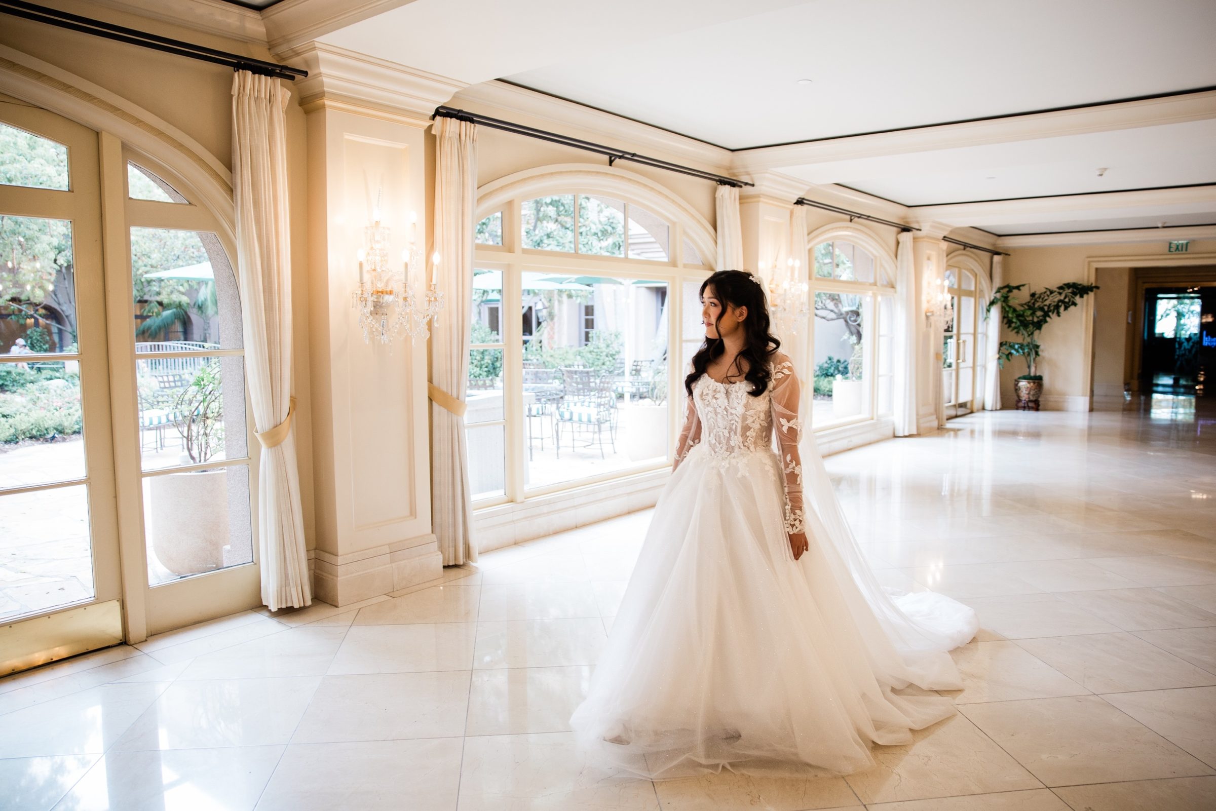 Candice walking through a hall of arched windows at the Langham Huntington on her way to Mass