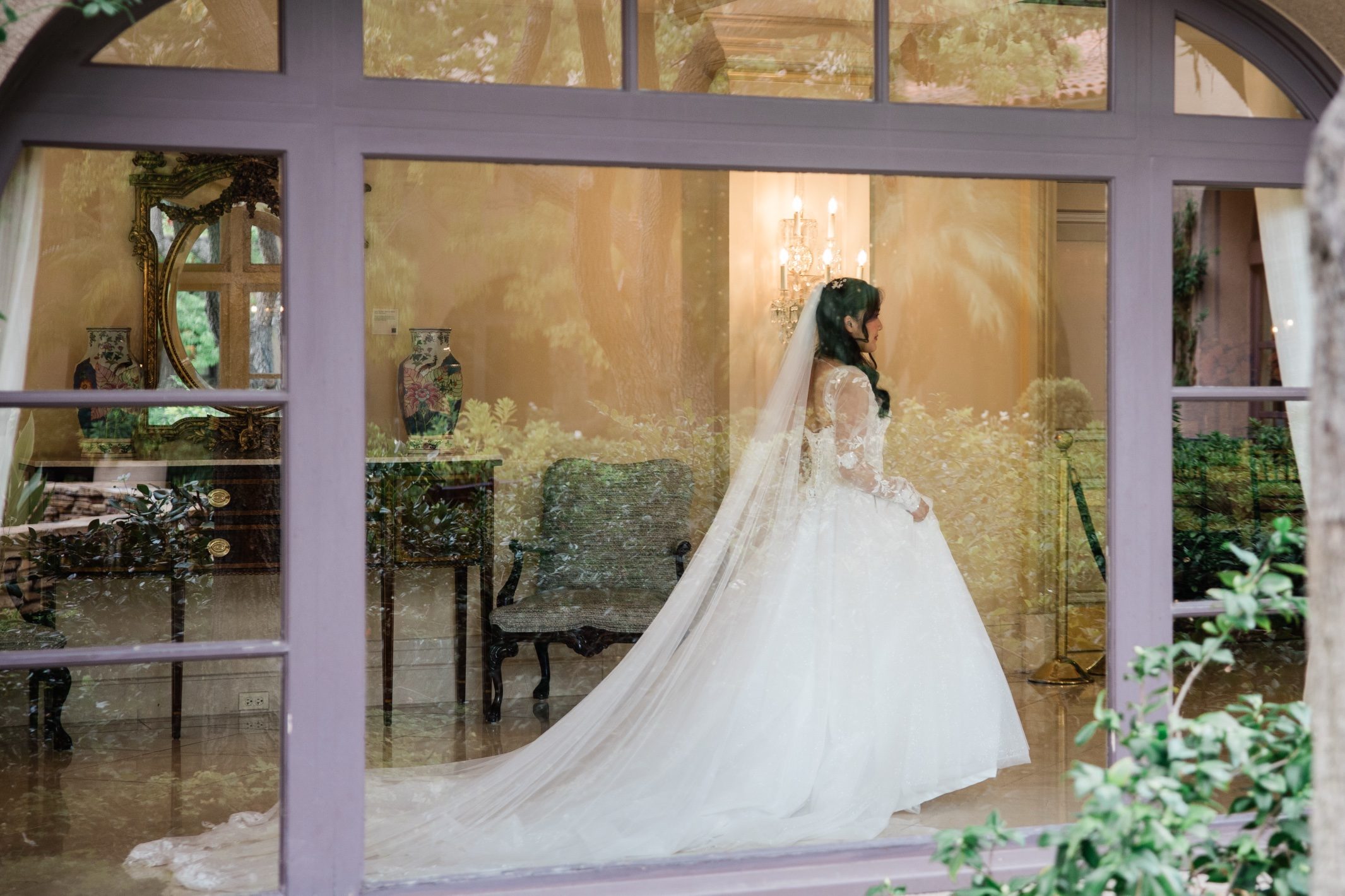Candice seen through a garden window as she leaves the hotel for the church