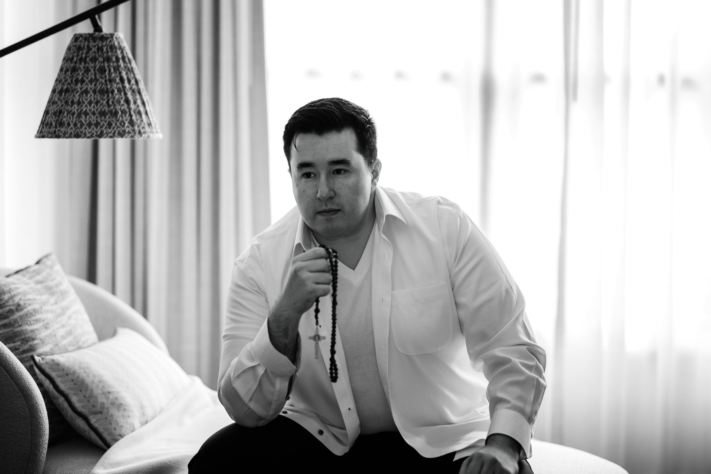 Black and white of Andrew holding a rosary before the wedding