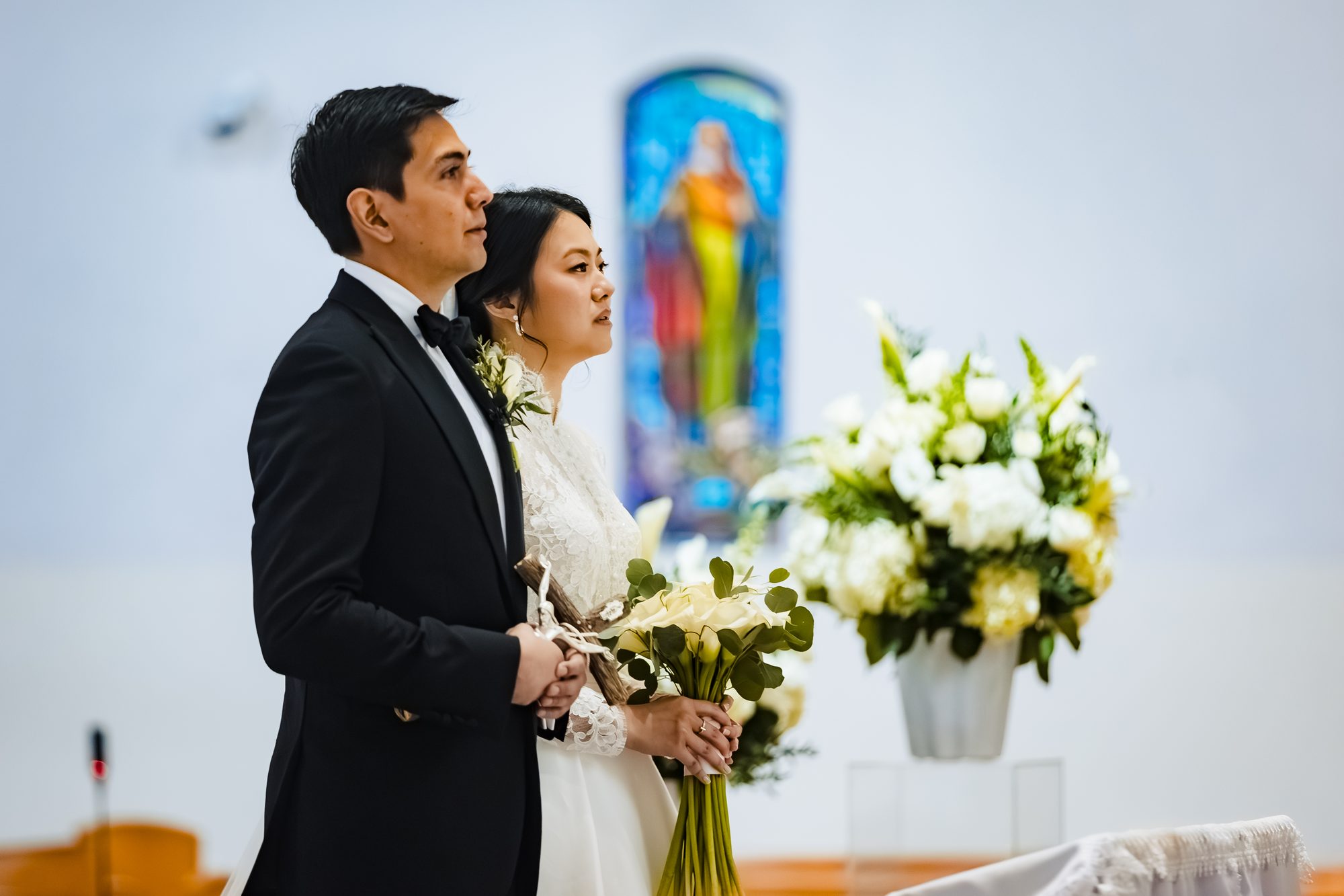 The bride veiled, holding white calla lilies