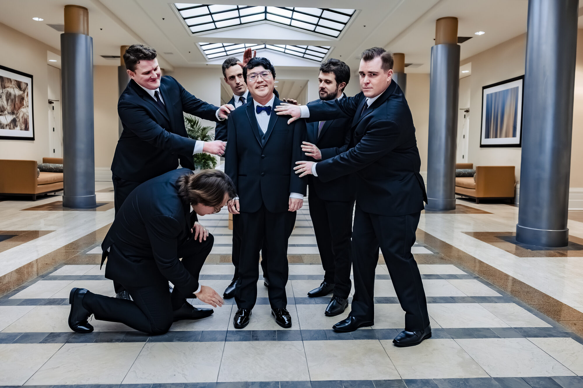 Groom and groomsmen in black suits with burgundy ties before the Nuptial Mass