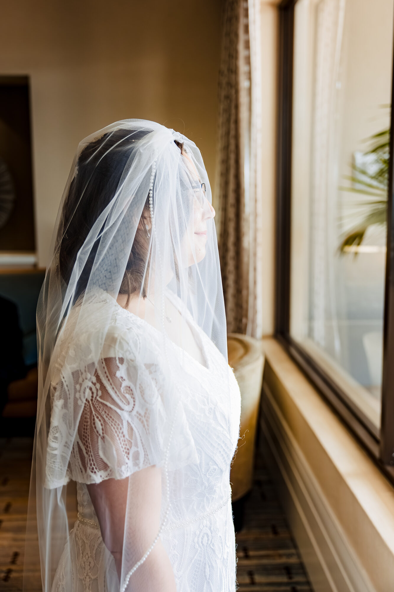 Bride in her lace cap-sleeve dress and pearl-trim veil at the Sonesta