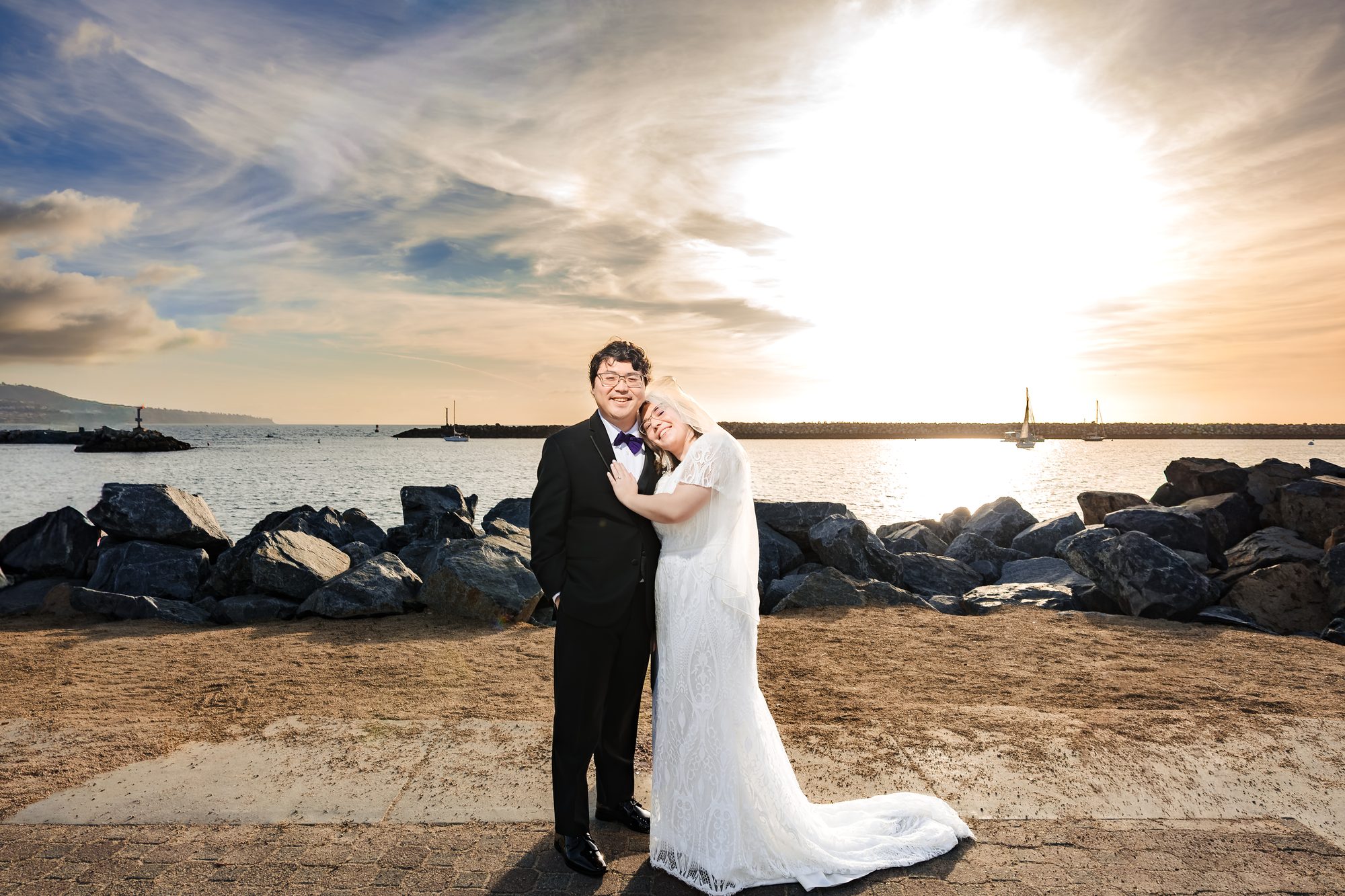 Bride and groom embrace at sunset on the Redondo Beach breakwater