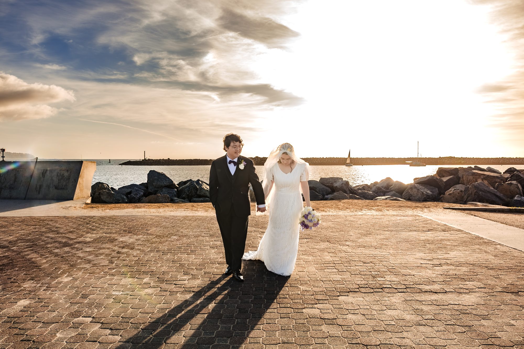 Brett and Kristen walking the breakwater with the bouquet in the golden California light
