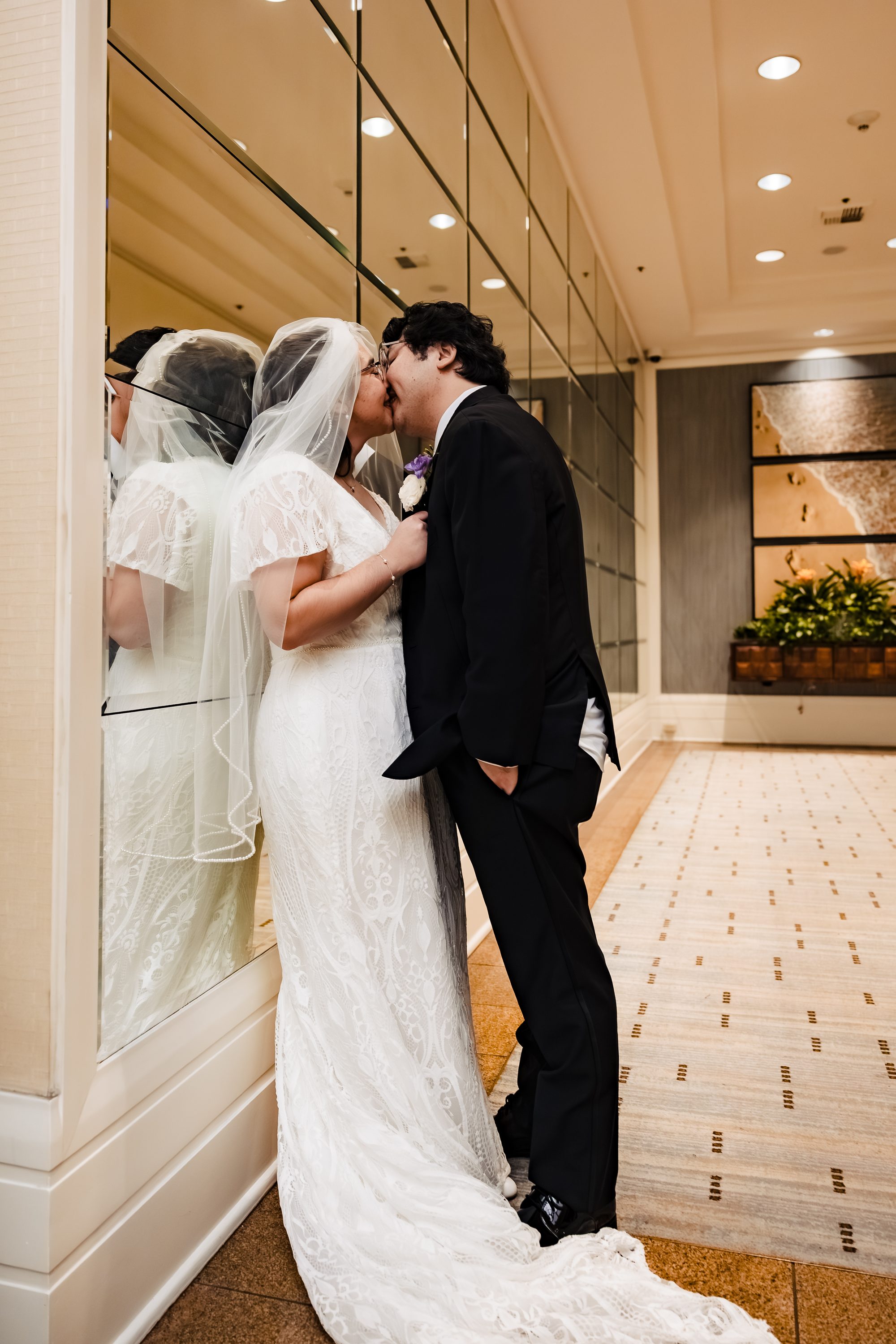Bride and groom share a kiss beside the mirrored wall at the Sonesta hotel
